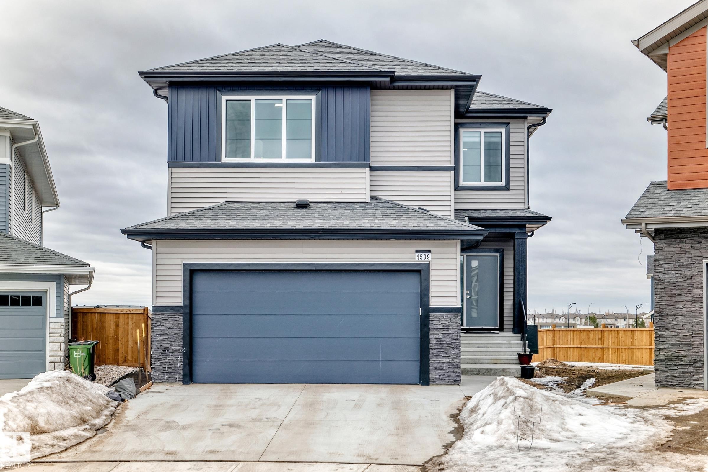 The property features a two-story exterior with light-colored siding and dark blue accents - 4509 170A Avenue, Edmonton, AB - Outdoor