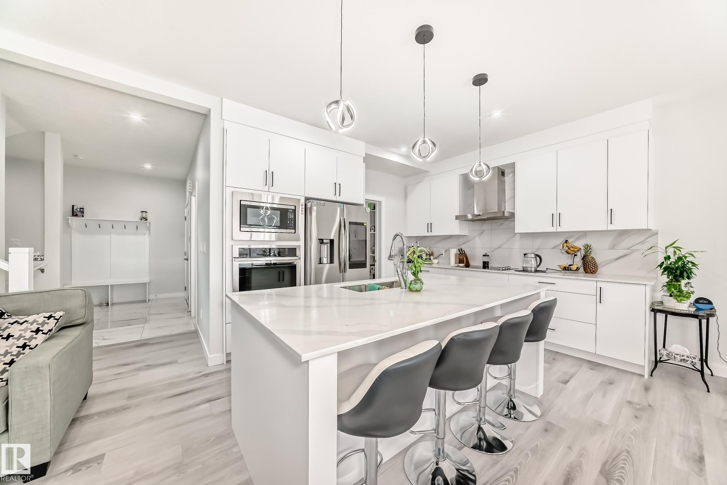 The kitchen features a large island with seating, pendant lighting, stainless steel appliances, and white cabinetry - 4509 170A Avenue, Edmonton, AB - Indoor Photo Showing Kitchen With Stainless Steel Kitchen With Upgraded Kitchen