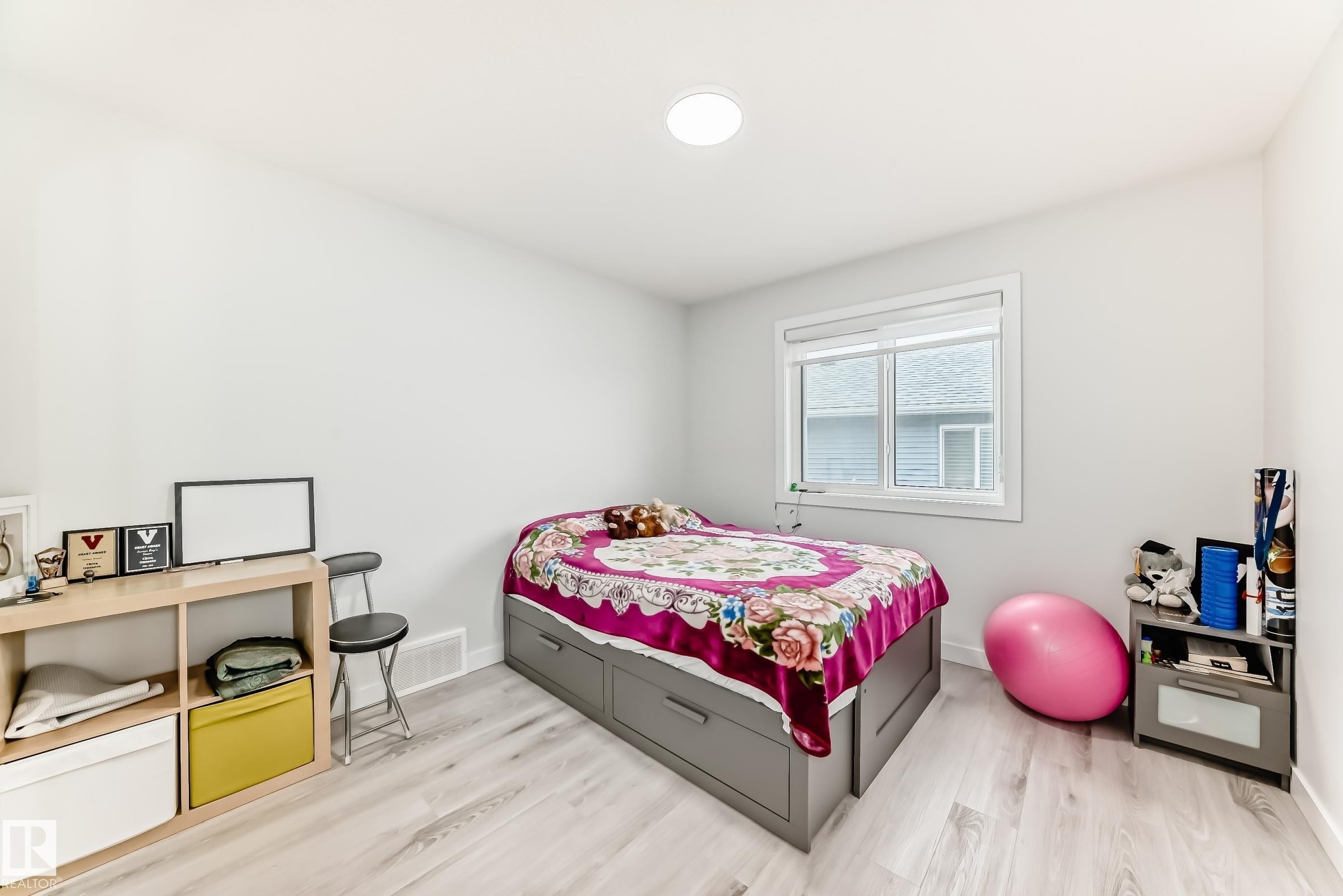 This room features light-colored walls, light wood-look flooring, and a window with white blinds - 4509 170A Avenue, Edmonton, AB - Indoor Photo Showing Bedroom