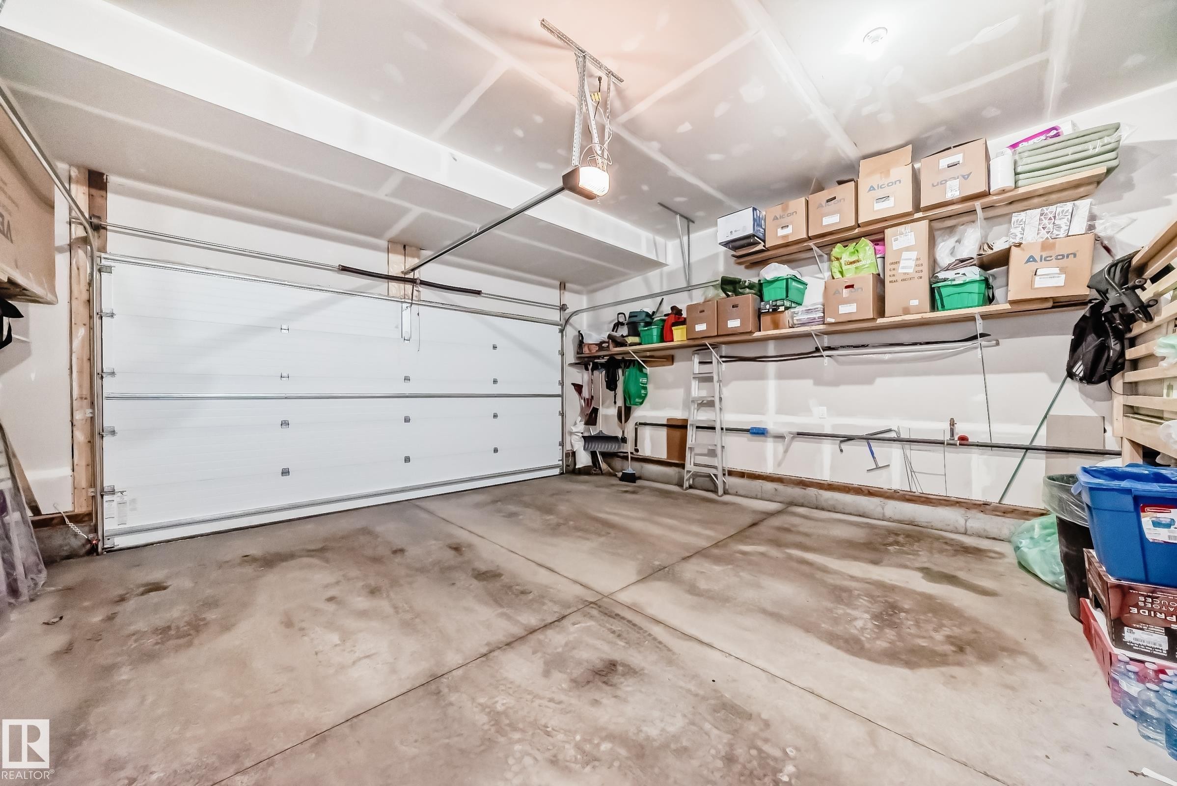 The property features a garage with a white garage door, concrete flooring, and overhead lighting - 4509 170A Avenue, Edmonton, AB - Indoor Photo Showing Garage