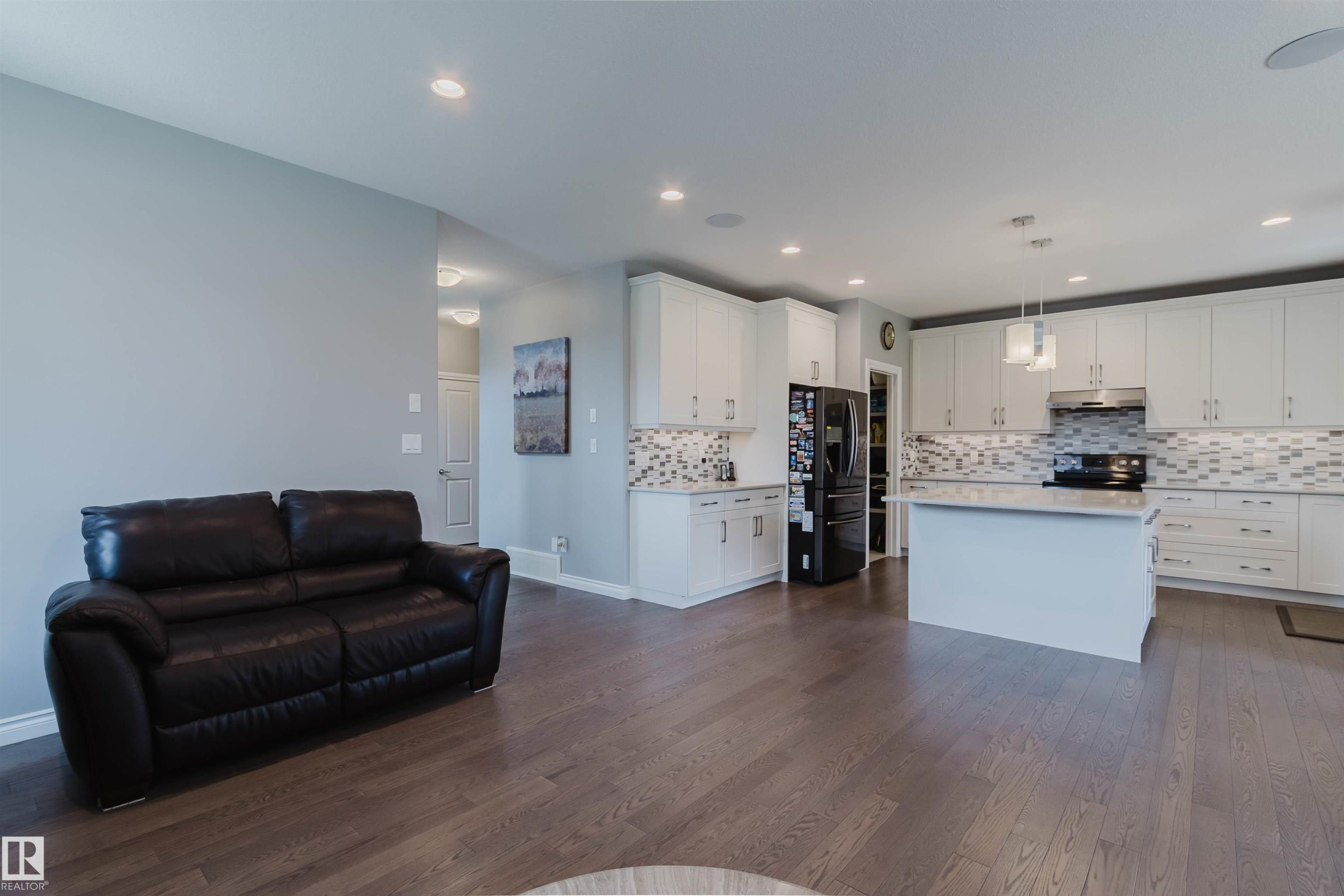 Open-concept living space featuring wood-finish flooring, recessed lighting, and a contemporary kitchen - 3571 Keswick Boulevard, Edmonton, AB - Indoor Photo Showing Kitchen With Upgraded Kitchen