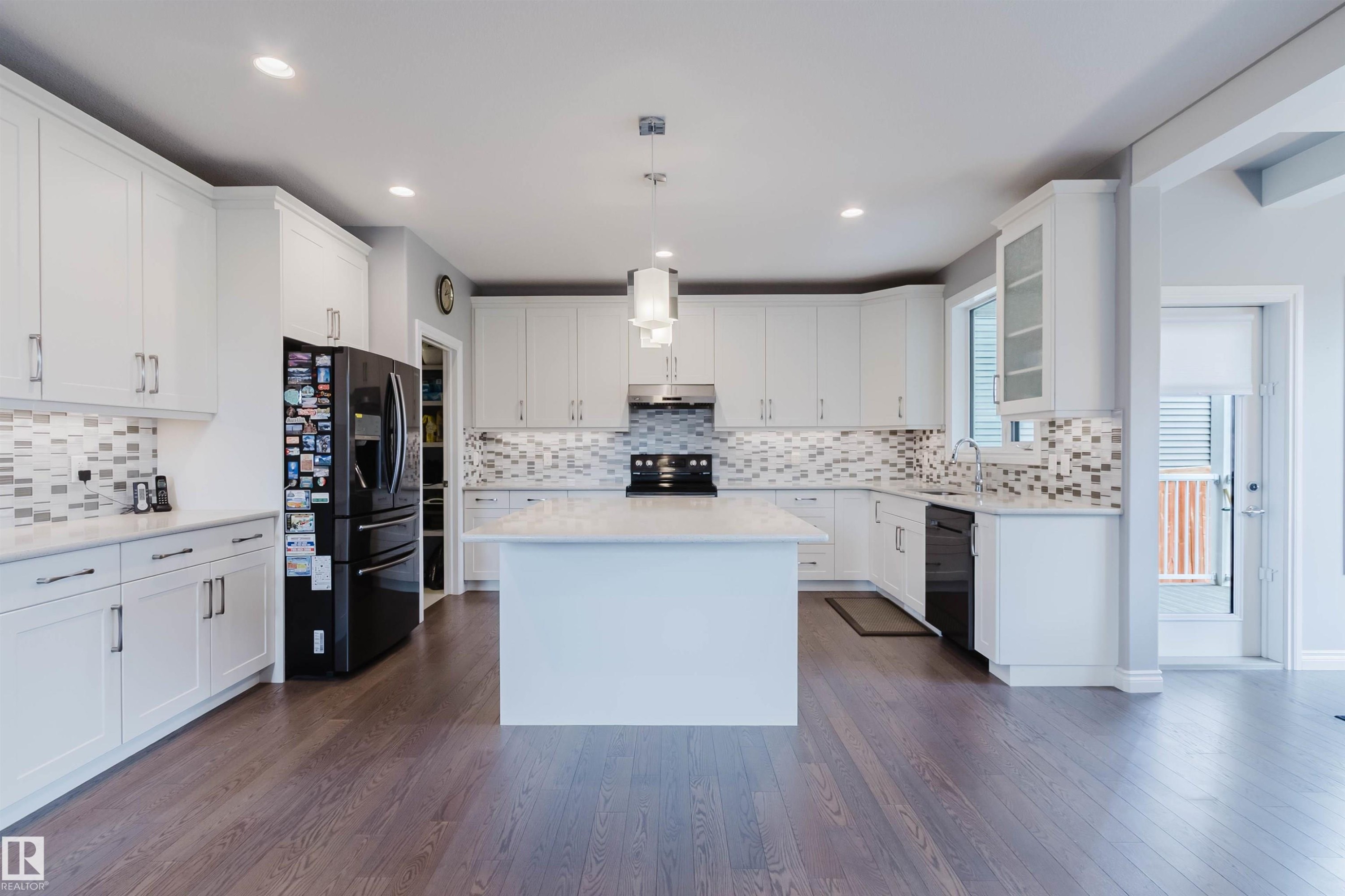 Spacious kitchen featuring white cabinetry, a center island with countertop, and wood-finish flooring - 3571 Keswick Boulevard, Edmonton, AB - Indoor Photo Showing Kitchen With Upgraded Kitchen
