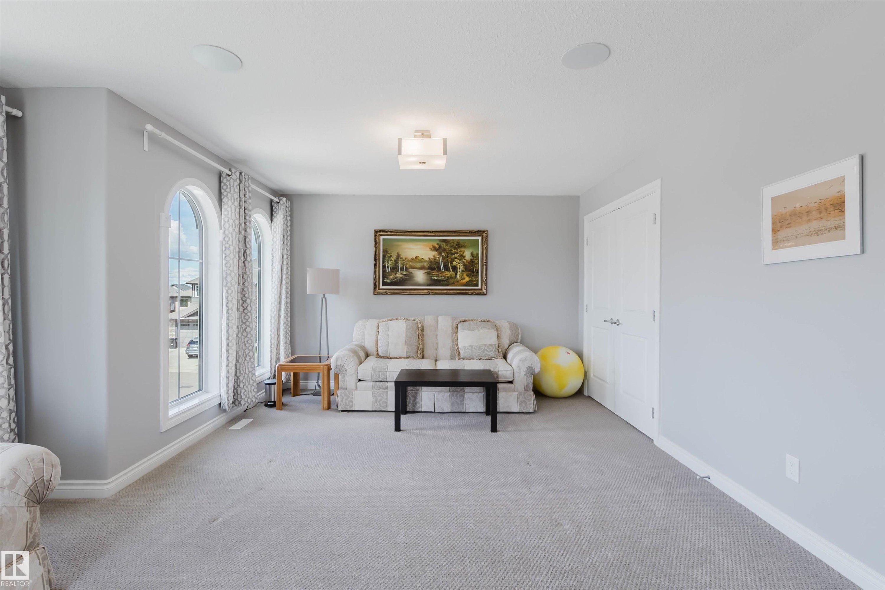 Spacious room featuring light grey carpeting and two arched windows - 3571 Keswick Boulevard, Edmonton, AB - Indoor Photo Showing Living Room