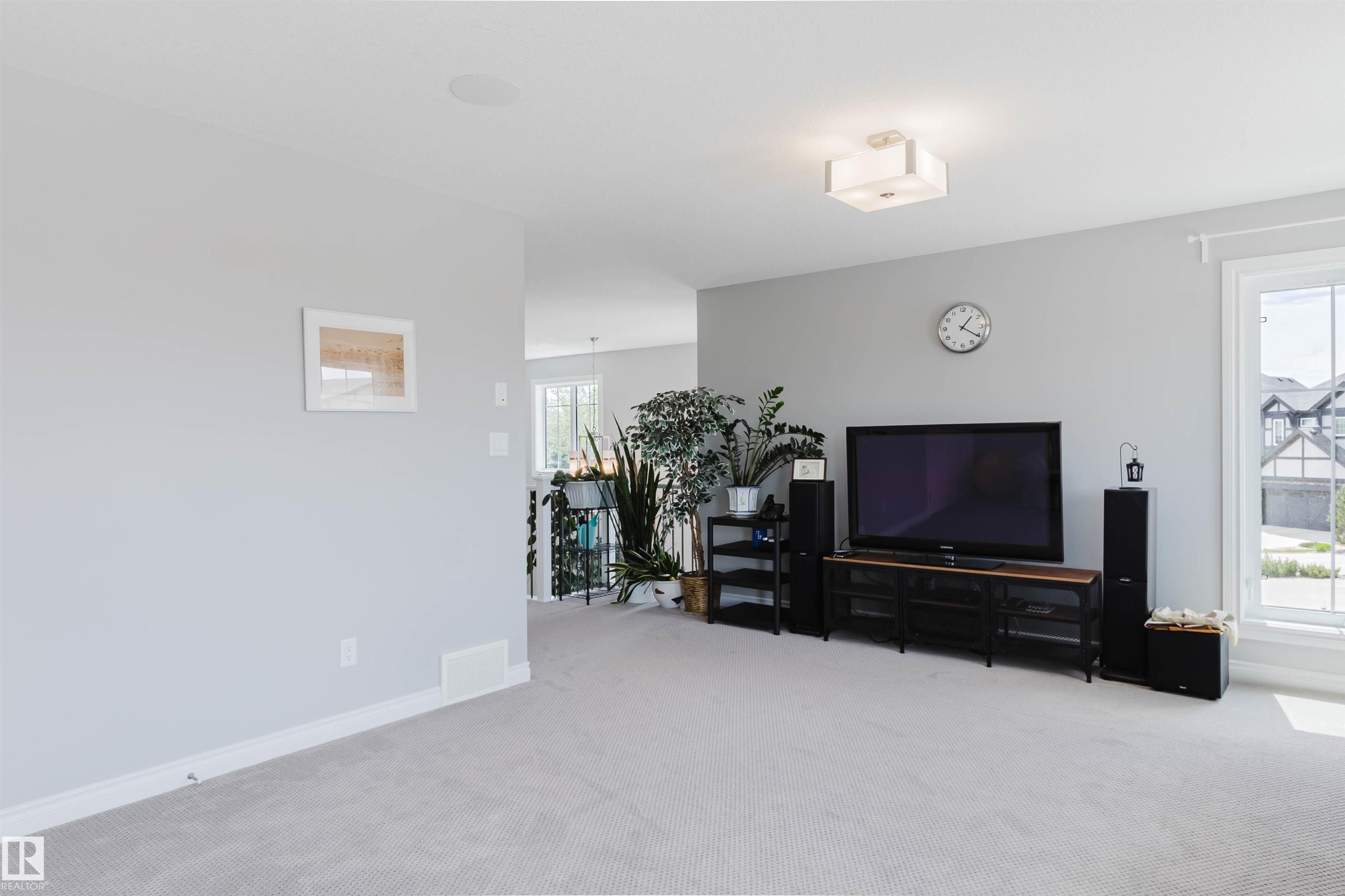Carpeted living area featuring light gray walls, white trim, and a contemporary flush-mount ceiling light - 3571 Keswick Boulevard, Edmonton, AB - Indoor