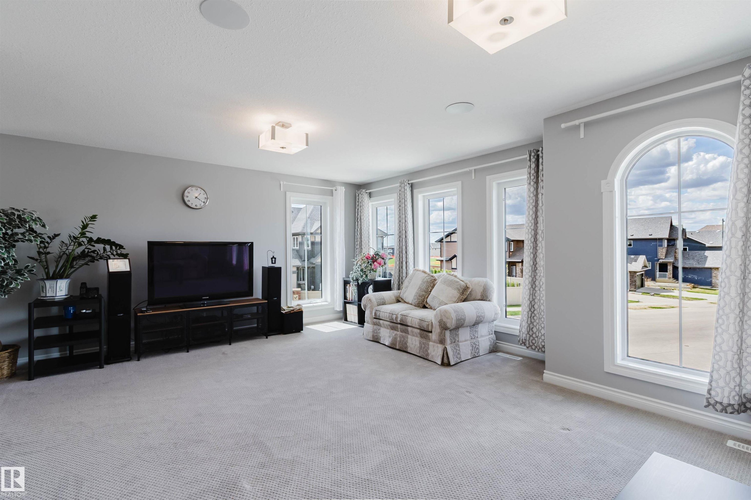 Spacious room featuring light gray walls, plush carpeting, multiple windows including one arched window, and recessed ceiling lighting - 3571 Keswick Boulevard, Edmonton, AB - Indoor Photo Showing Living Room