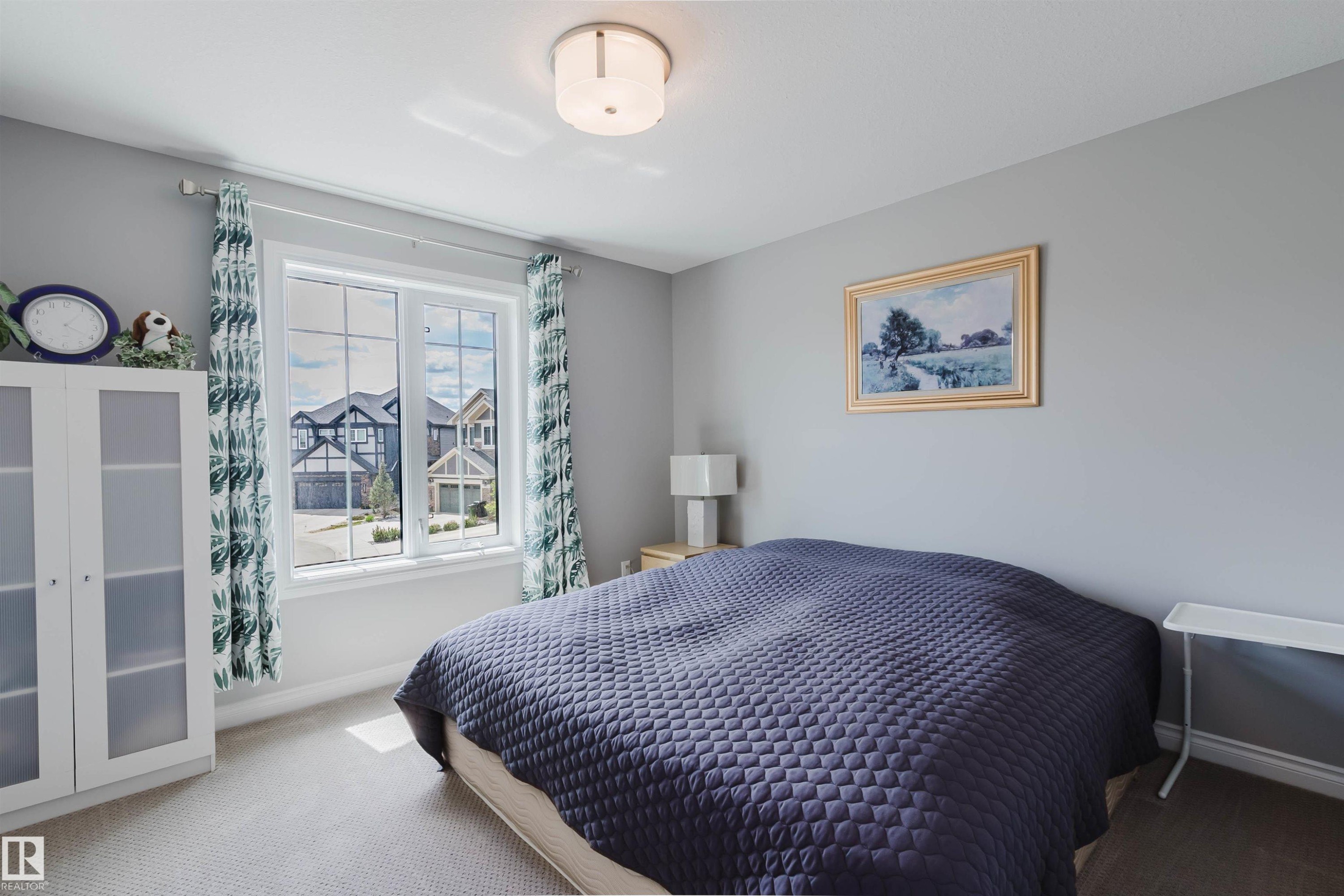 Bright room featuring a large window with white framing, light gray walls, and light-colored carpeting - 3571 Keswick Boulevard, Edmonton, AB - Indoor Photo Showing Bedroom