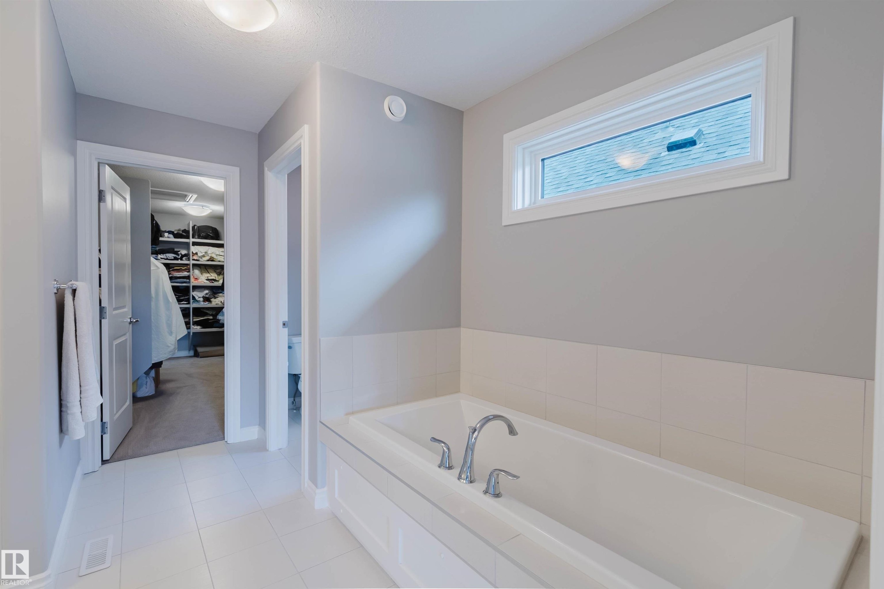 Soaking tub with chrome fixtures, set against a tiled wainscoting - 3571 Keswick Boulevard, Edmonton, AB - Indoor Photo Showing Bathroom
