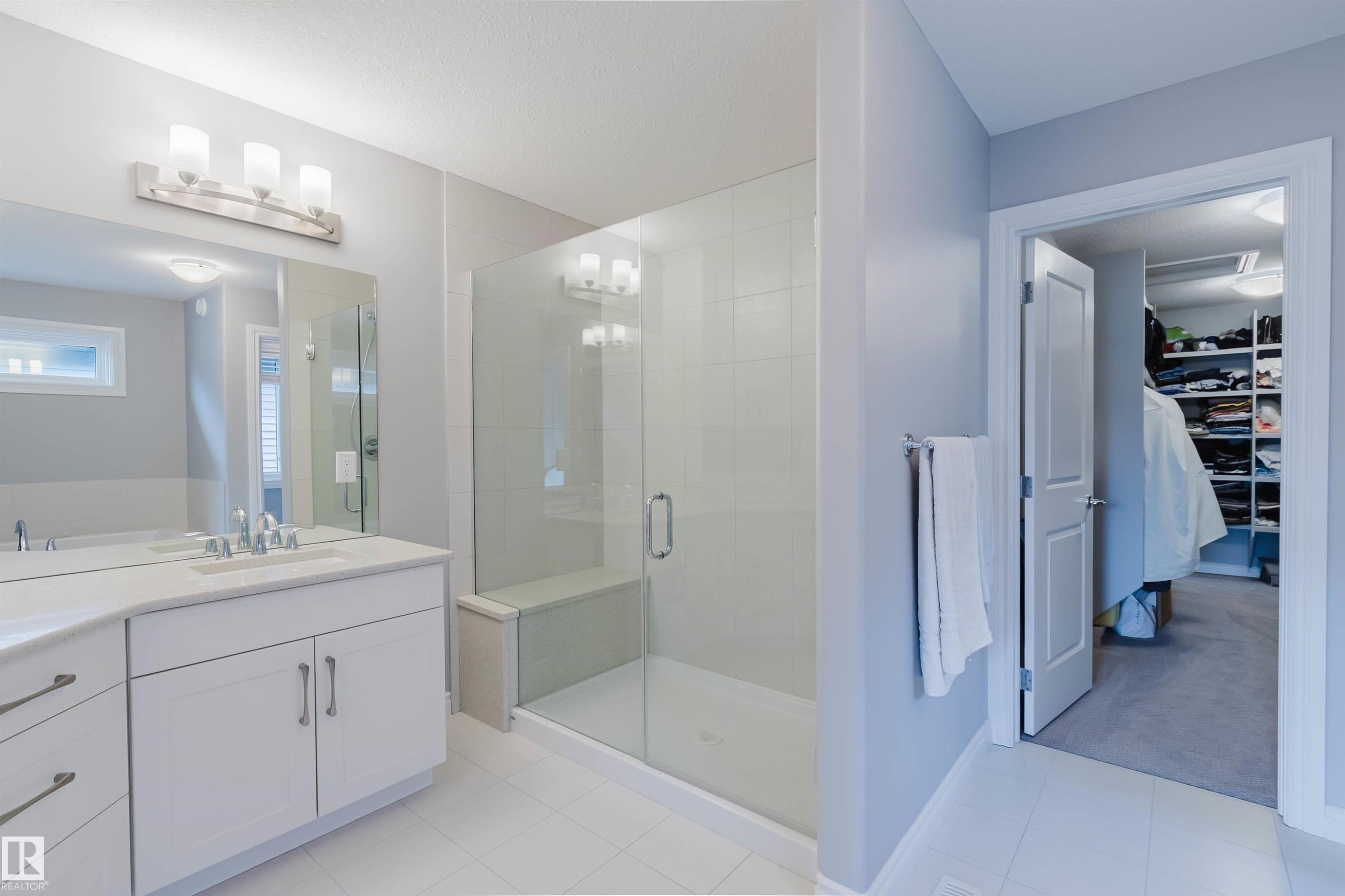 Bathroom featuring a double vanity with white cabinetry, a large mirror, and a glass-enclosed shower with a built-in bench - 3571 Keswick Boulevard, Edmonton, AB - Indoor Photo Showing Bathroom