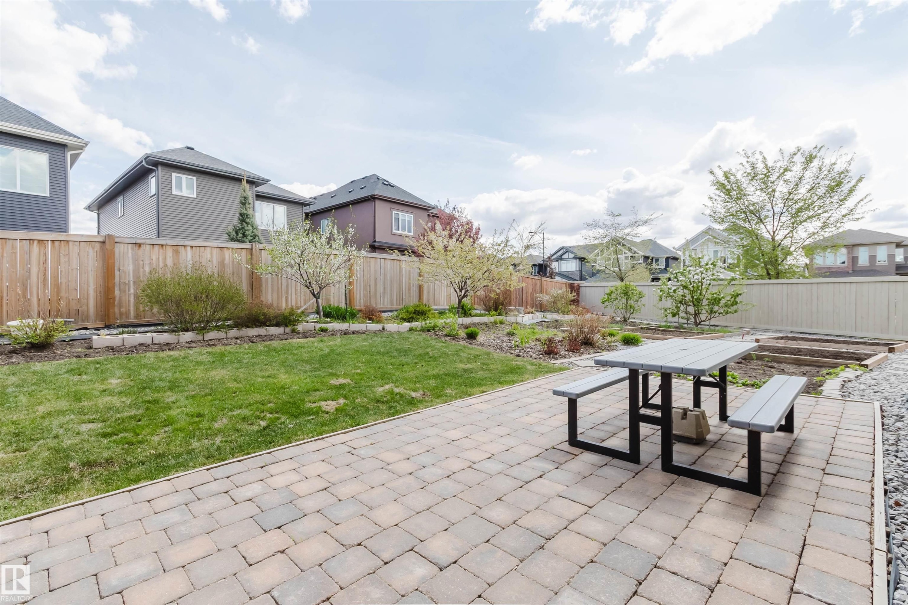Expansive backyard featuring a paver patio, manicured lawn, and raised garden beds - 3571 Keswick Boulevard, Edmonton, AB - Outdoor