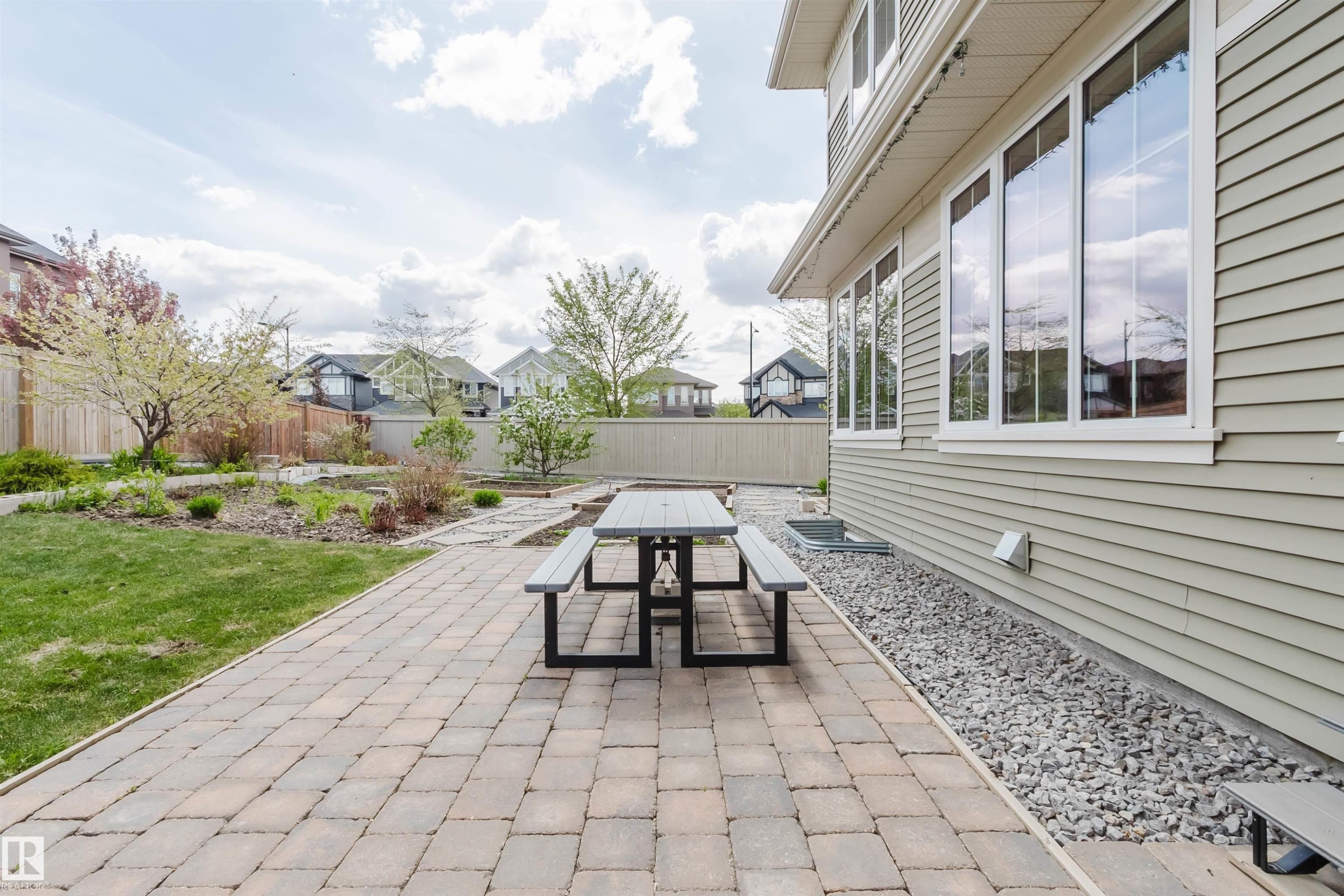 Expansive paver patio bordered by a rock bed and siding exterior - 3571 Keswick Boulevard, Edmonton, AB - Outdoor With Deck Patio Veranda