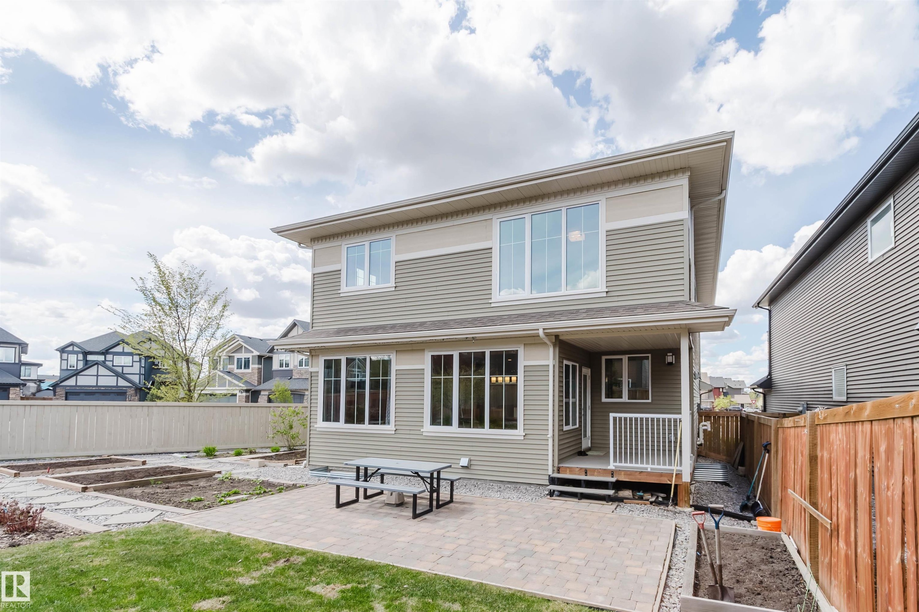 Rear exterior featuring horizontal siding, multiple windows, and a paved patio area - 3571 Keswick Boulevard, Edmonton, AB - Outdoor
