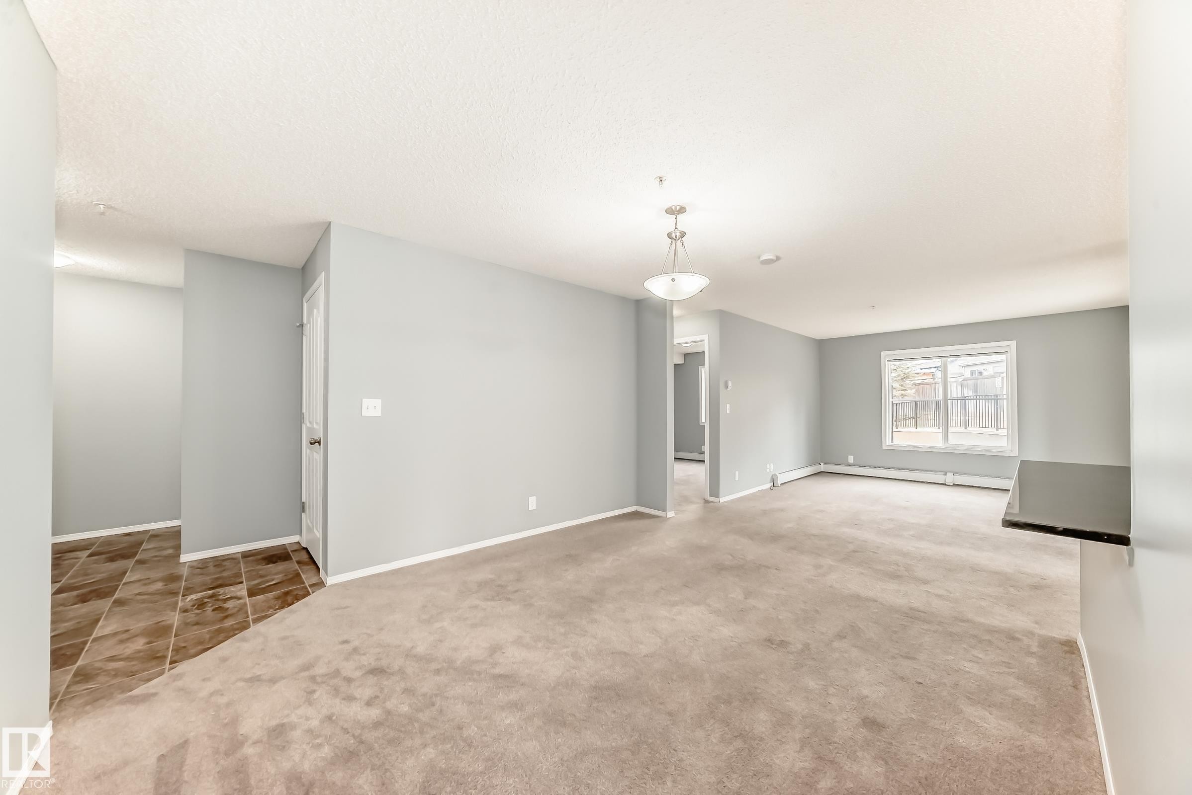 Living area featuring light grey walls, a carpeted floor, and a window providing natural light - 101 530 Watt Boulevard, Edmonton, AB - Indoor Photo Showing Other Room