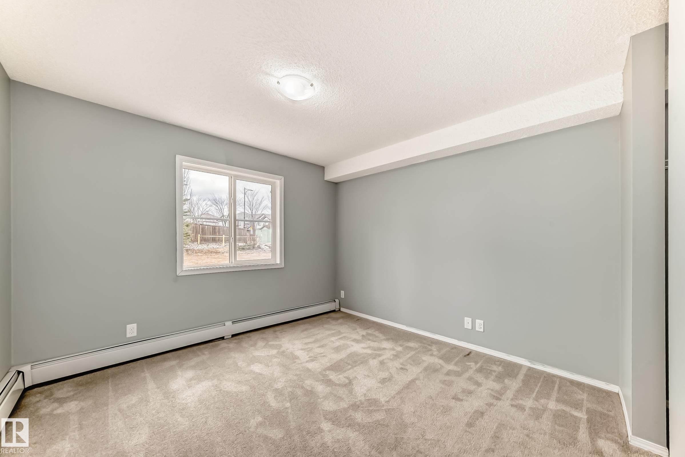 This room features neutral grey walls, light-colored carpeting, and a window providing natural light - 101 530 Watt Boulevard, Edmonton, AB - Indoor Photo Showing Other Room
