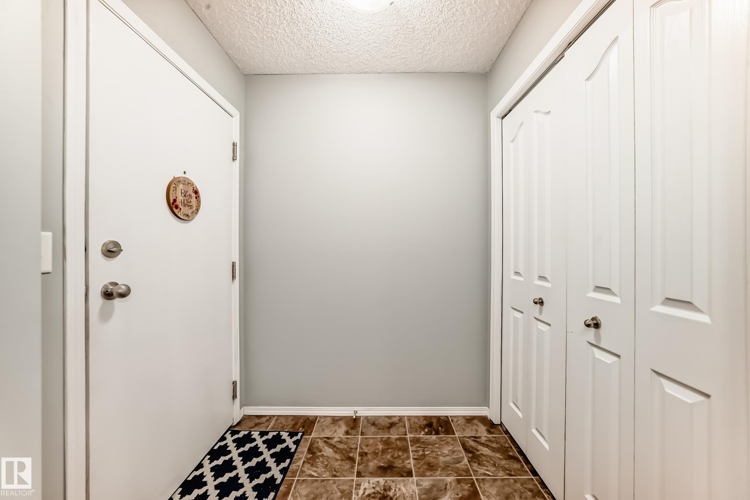 Entryway featuring a white door, light gray walls, and brown tiled flooring - 101 530 Watt Boulevard, Edmonton, AB - Indoor Photo Showing Other Room