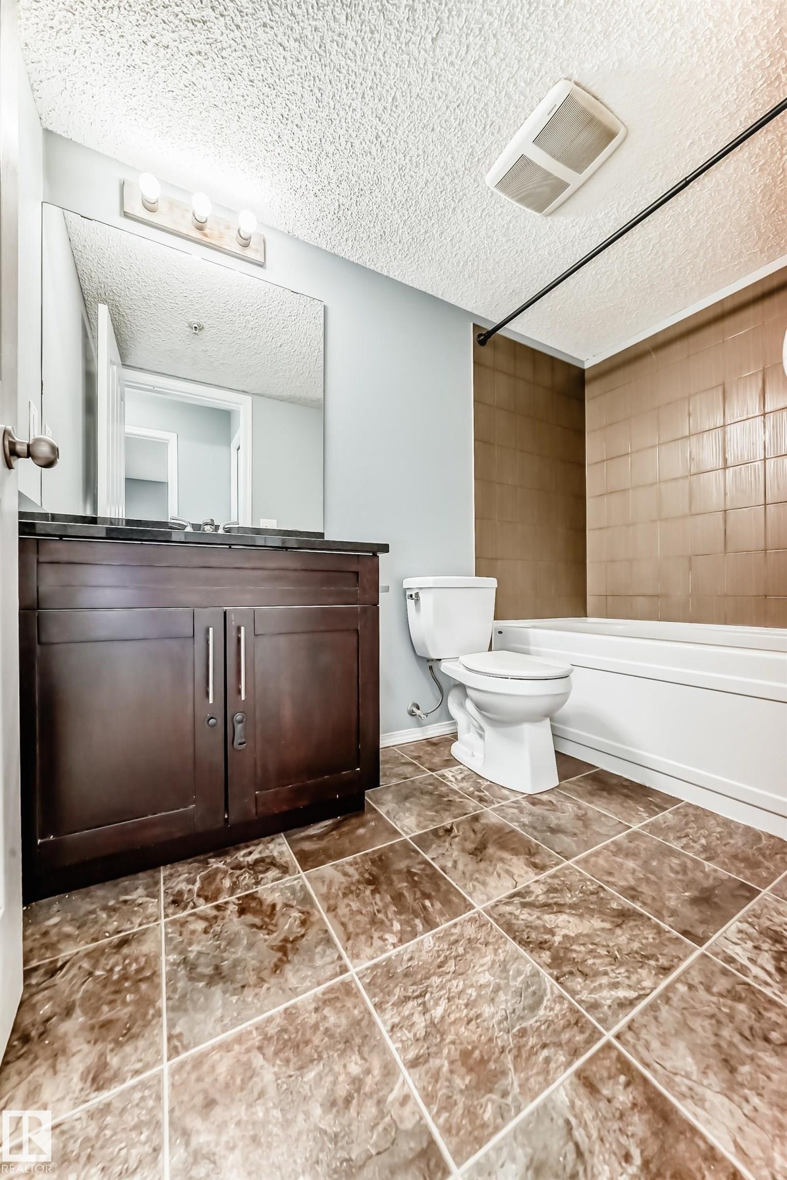 Bathroom featuring a dark wood vanity with a dark countertop, a mirror, and tiled flooring - 101 530 Watt Boulevard, Edmonton, AB - Indoor Photo Showing Bathroom