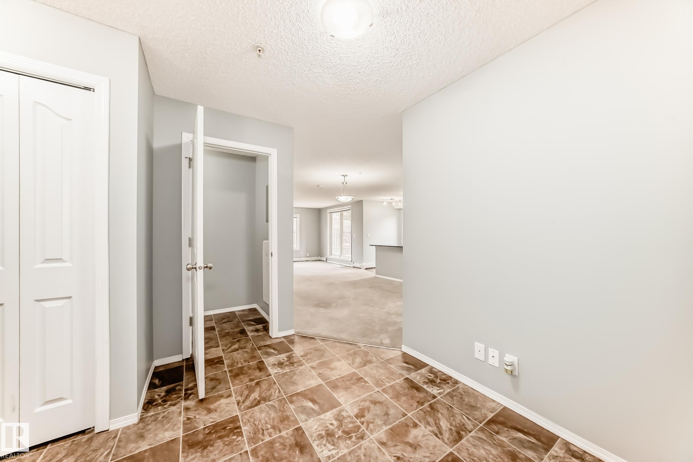 Entrance featuring patterned floor tiles and light-colored walls, leading into a carpeted interior - 101 530 Watt Boulevard, Edmonton, AB - Indoor Photo Showing Other Room