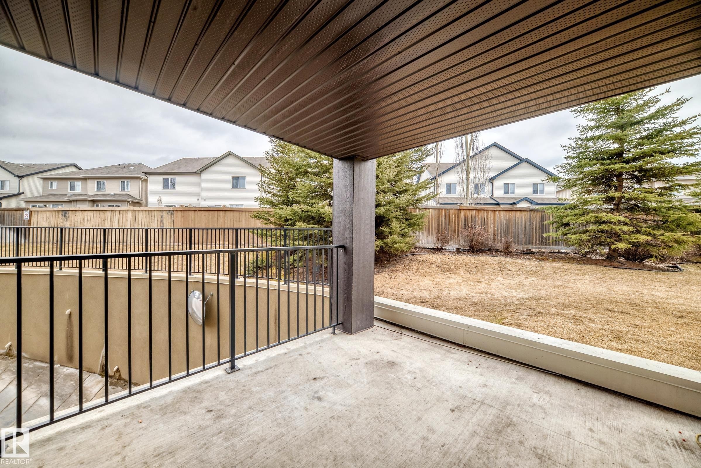 The property features a covered patio with a concrete surface and a black metal railing - 101 530 Watt Boulevard, Edmonton, AB - Outdoor With Exterior