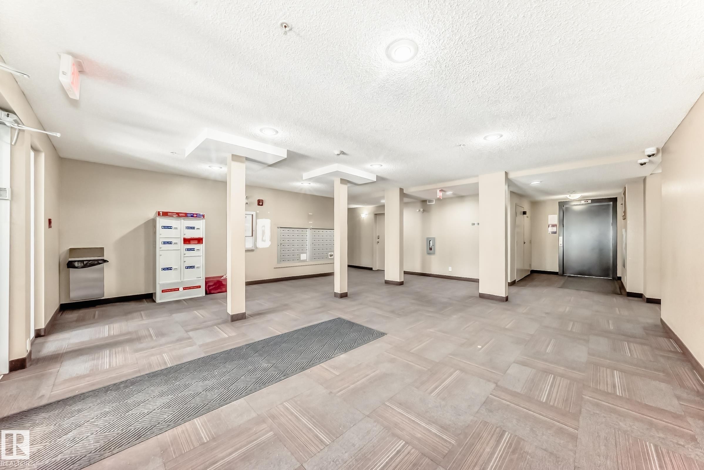 The property features a spacious common area with tiled flooring, recessed lighting, and access to mailboxes - 101 530 Watt Boulevard, Edmonton, AB - Indoor Photo Showing Other Room