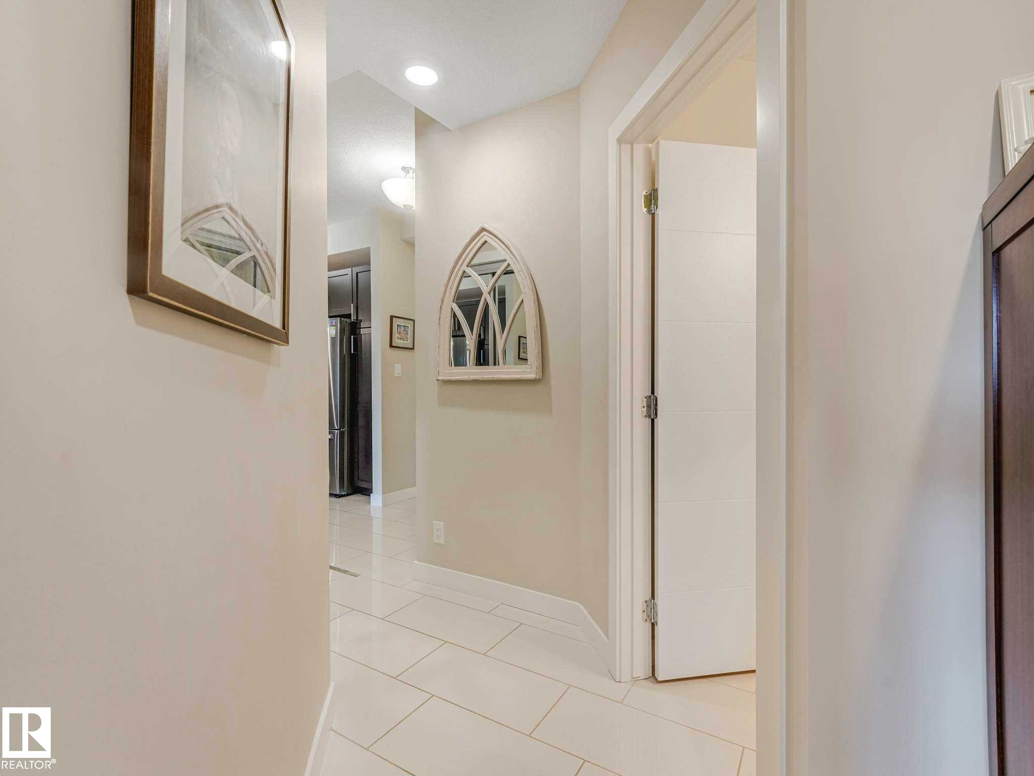 Hallway featuring neutral wall tones, recessed lighting, and rectangular tile flooring - 213 625 Leger Way, Edmonton, AB - Indoor Photo Showing Other Room