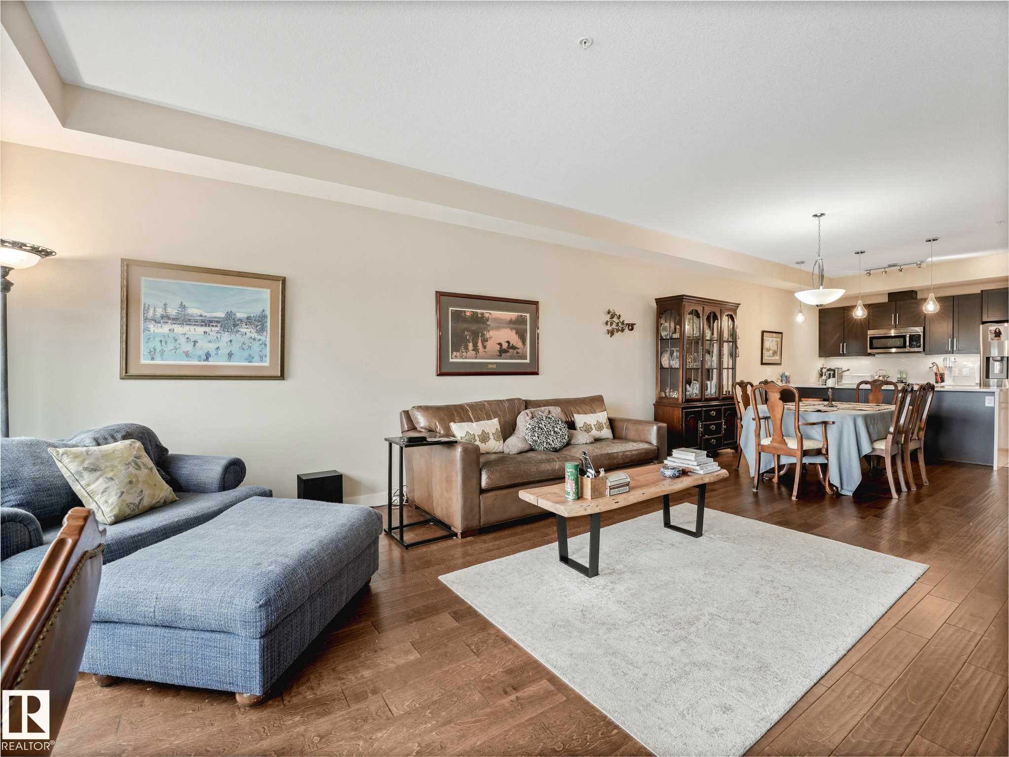 Open-concept living space featuring wood-finish flooring, recessed lighting, and tray ceiling details - 213 625 Leger Way, Edmonton, AB - Indoor Photo Showing Living Room