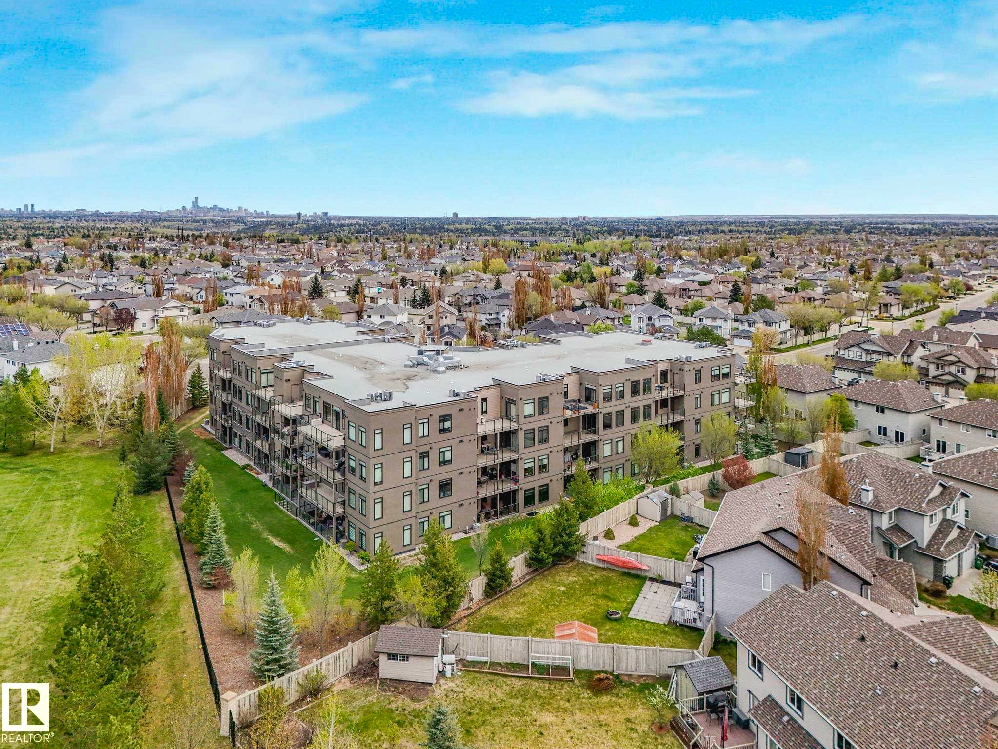 Modern multi-story building featuring balconies and a surrounding green space - 213 625 Leger Way, Edmonton, AB - Outdoor With View