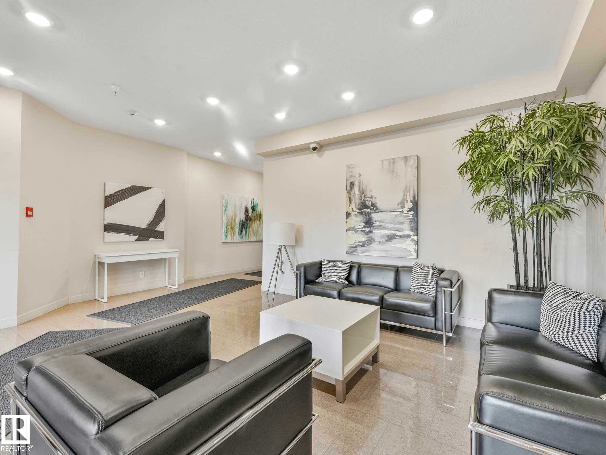 Lobby area featuring polished tile flooring, recessed ceiling lighting, and a white console table - 213 625 Leger Way, Edmonton, AB - Indoor