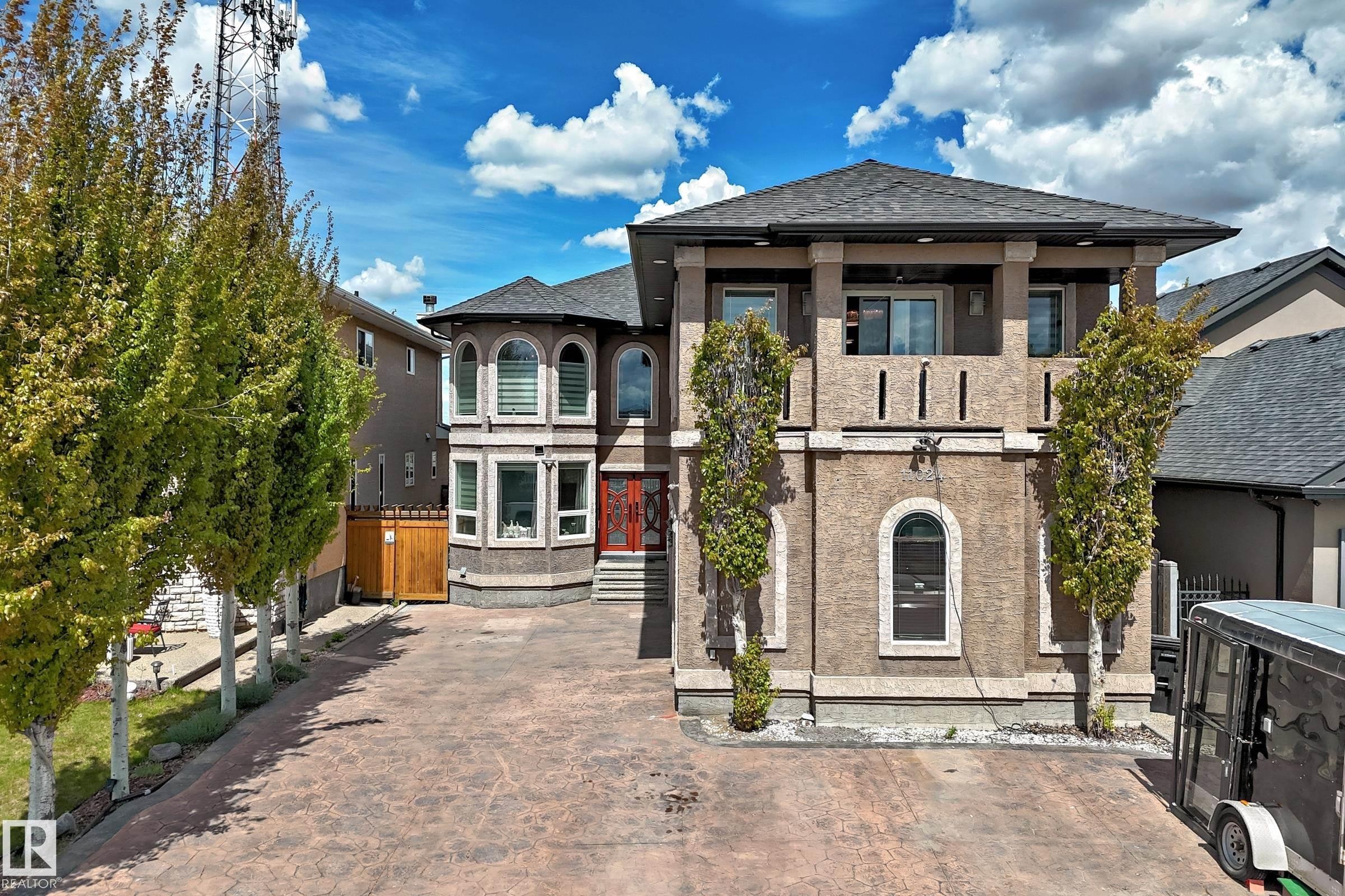 Stucco exterior featuring a double door entry way, stamped concrete driveway, and mature landscaping - 11024 179 Avenue, Edmonton, AB - Outdoor