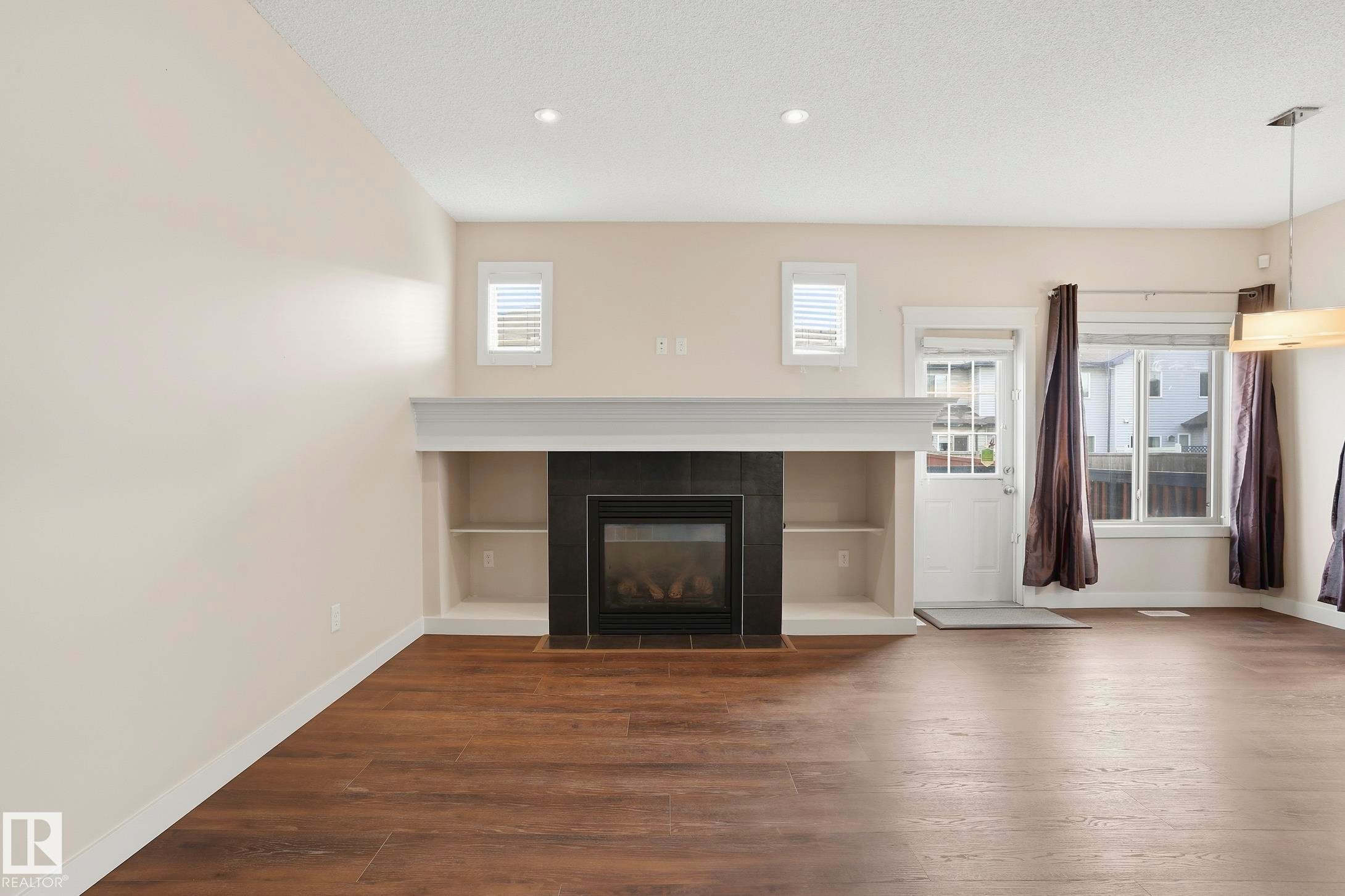Living space featuring a built-in fireplace with black surround, integrated shelving, and a substantial mantel - 2917 16A Avenue, Edmonton, AB - Indoor Photo Showing Living Room With Fireplace