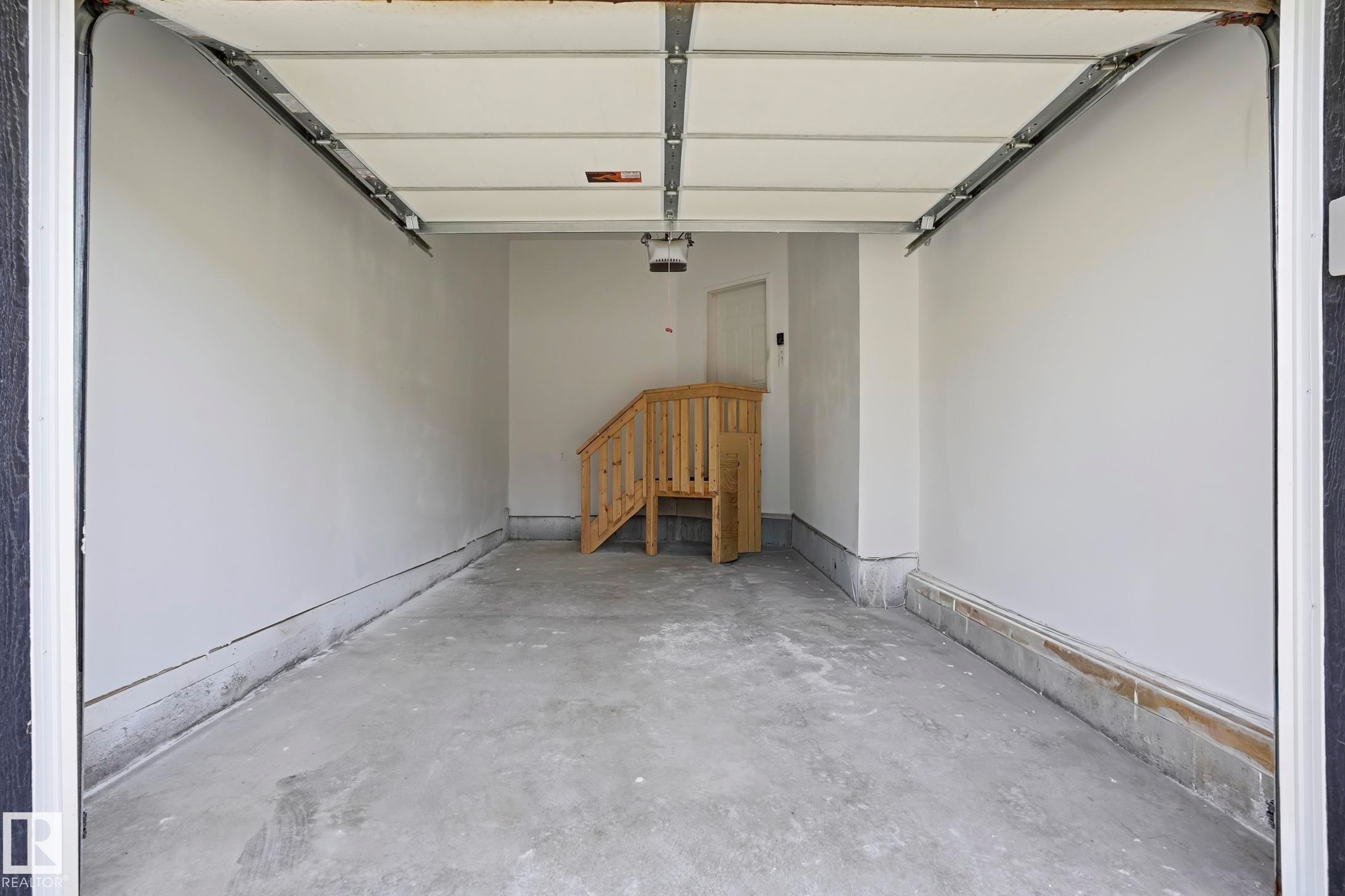 Spacious garage featuring a concrete floor, painted walls, an overhead garage door, and a built-in wooden staircase - 2917 16A Avenue, Edmonton, AB - Indoor Photo Showing Garage