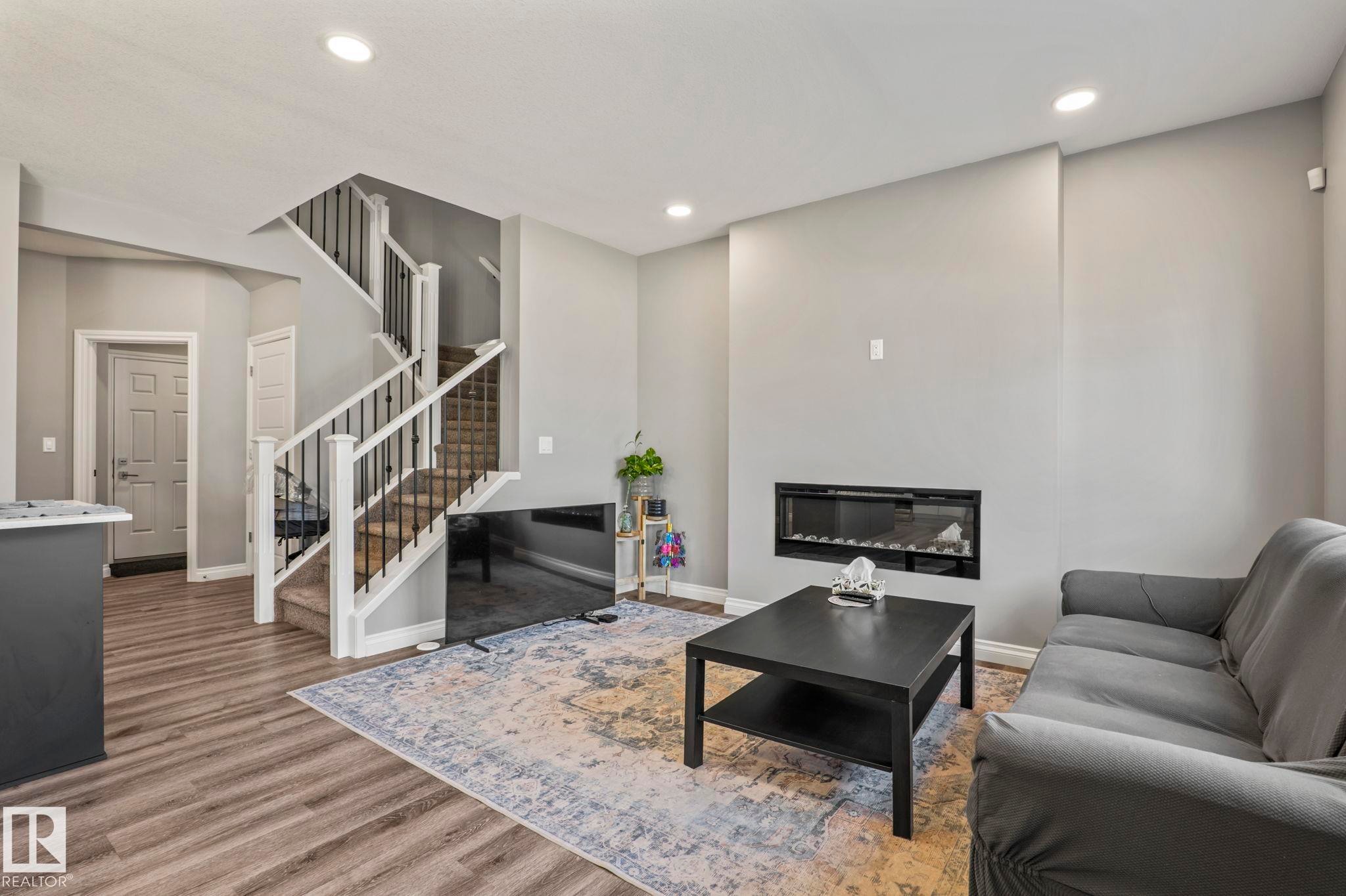 Spacious living area featuring wood-finish flooring, recessed lighting, and a contemporary linear fireplace - 5142 23A Avenue, Edmonton, AB - Indoor With Fireplace