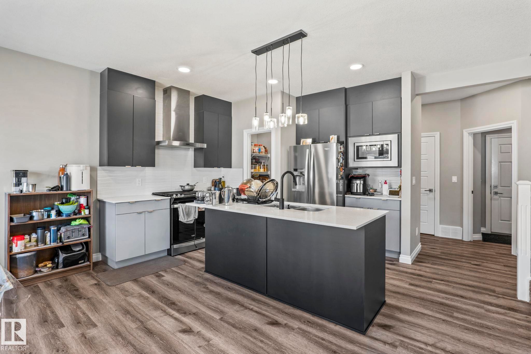 Contemporary kitchen featuring a dark gray island with a white countertop and a matte black faucet - 5142 23A Avenue, Edmonton, AB - Indoor Photo Showing Kitchen With Upgraded Kitchen