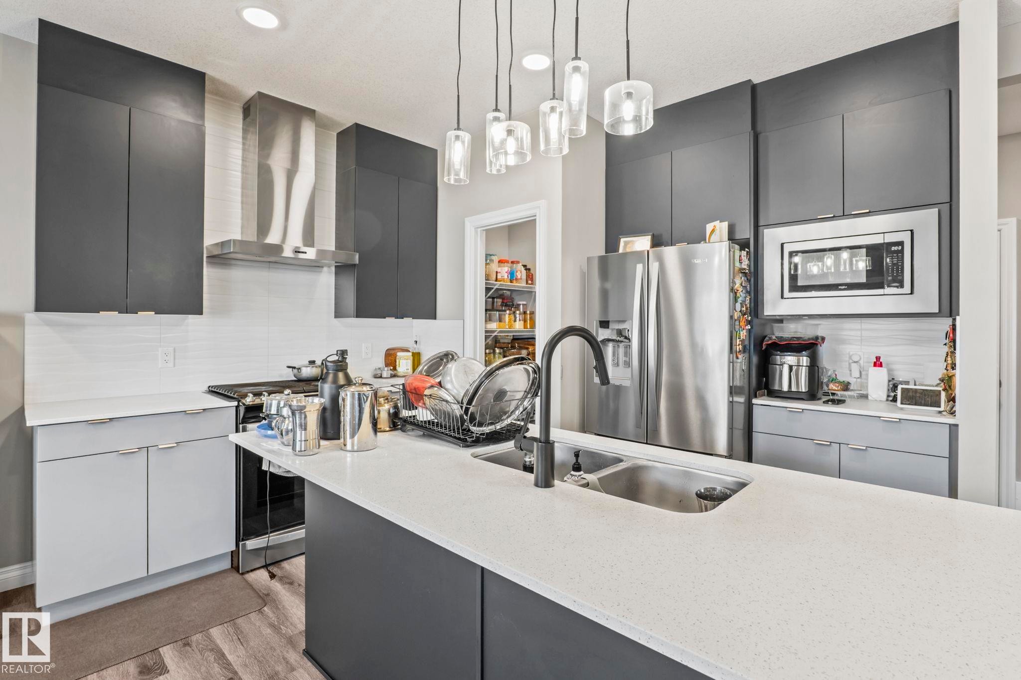 Modern kitchen featuring dark gray upper cabinetry, light gray lower cabinetry, and a light-toned countertop - 5142 23A Avenue, Edmonton, AB - Indoor Photo Showing Kitchen With Double Sink With Upgraded Kitchen
