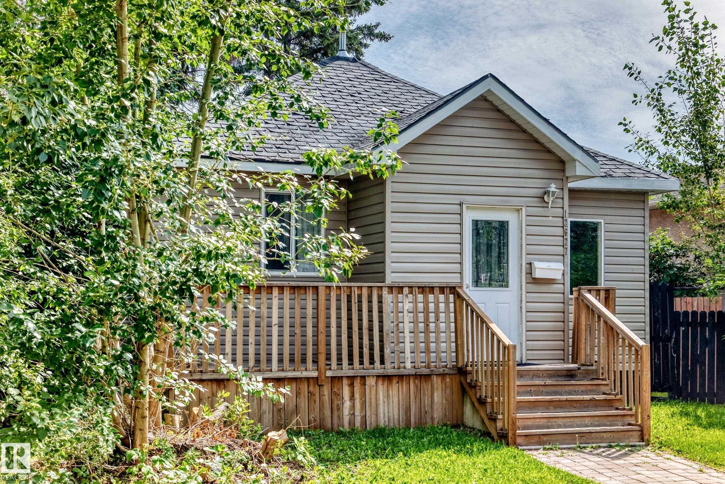 Exterior featuring horizontal siding, a gabled roofline, a front porch with wood railings, wood steps, and a paved walkway - 12627 71 Street Nw, Edmonton, AB