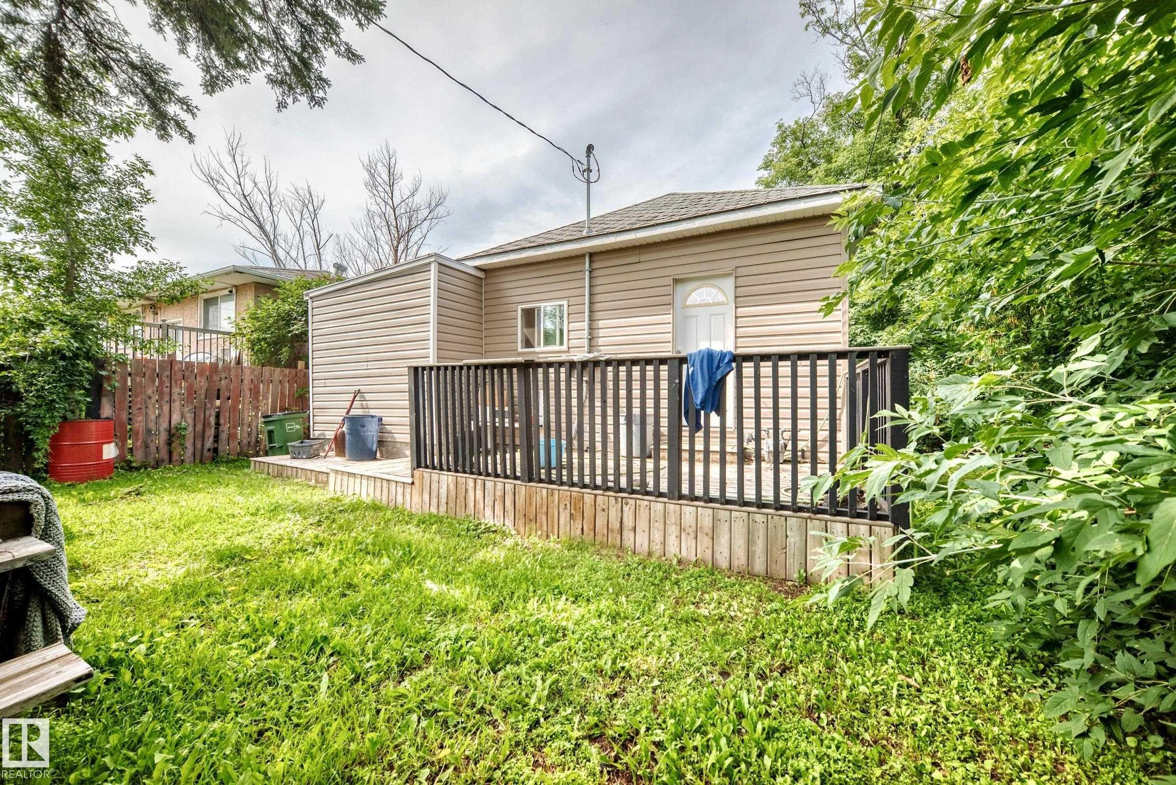 Rear exterior featuring horizontal siding, a private deck with black railings, and a fenced yard - 12627 71 Street Nw, Edmonton, AB
