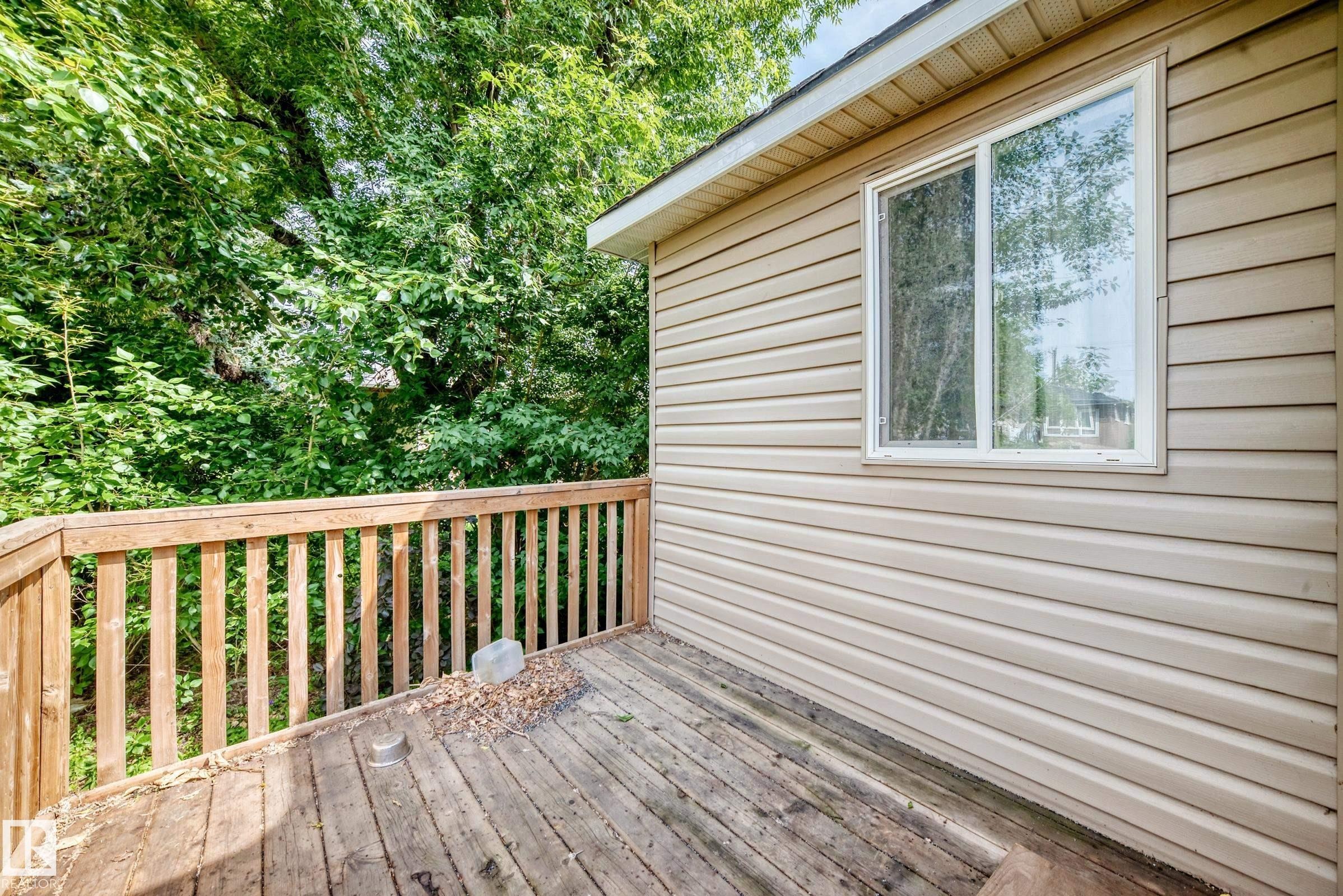 Outdoor deck with wood railings, wood-plank flooring, and tan horizontal siding - 12627 71 Street Nw, Edmonton, AB