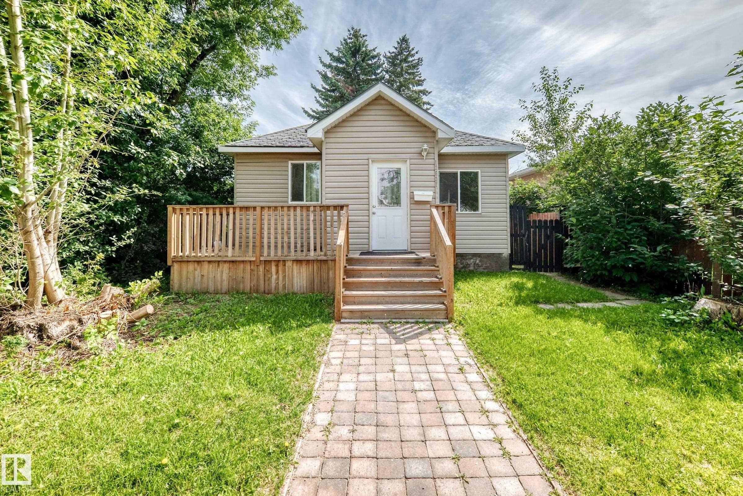 Siding exterior with a gable roof, featuring a wood deck and a brick paver walkway - 12627 71 Street Nw, Edmonton, AB