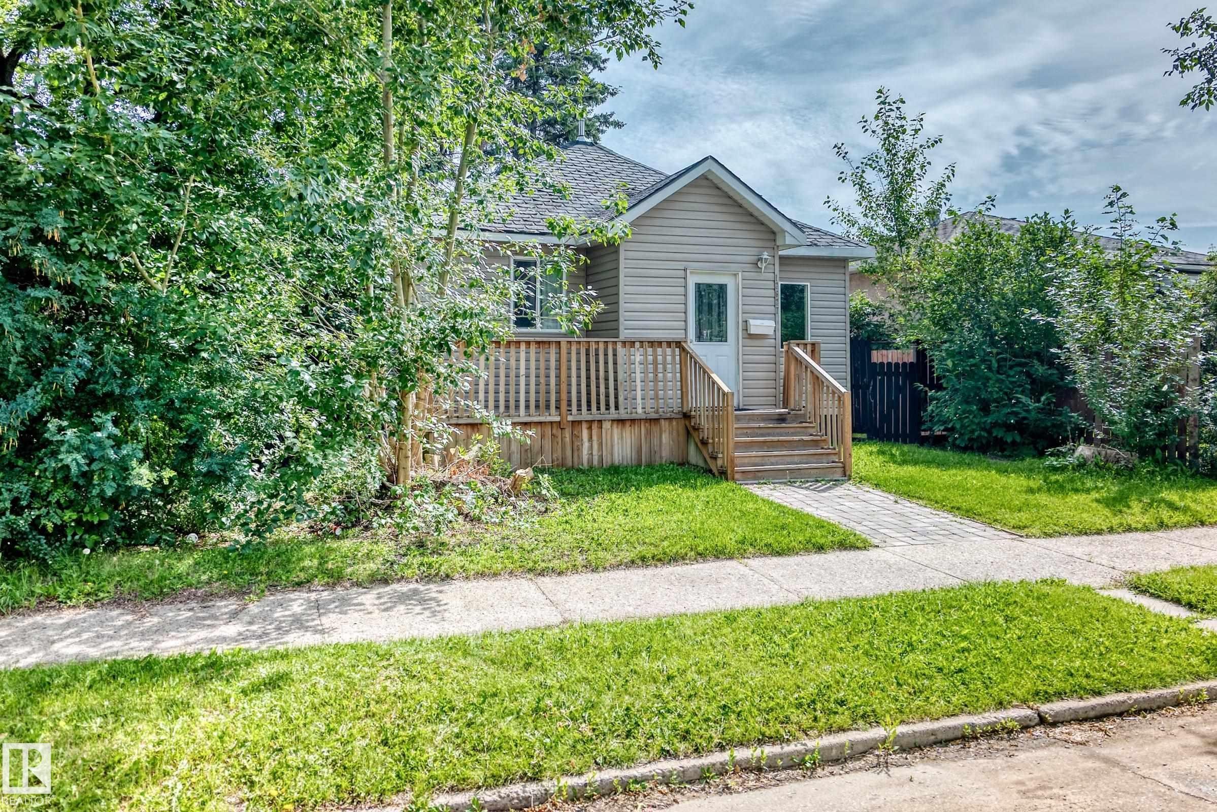 Siding exterior featuring a pitched roof, front porch with wood railings, and concrete walkway - 12627 71 Street Nw, Edmonton, AB