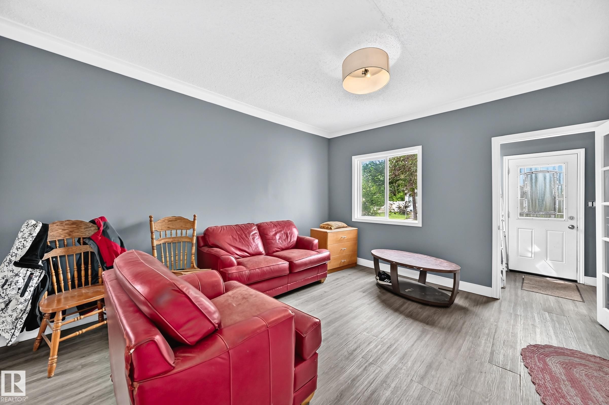 Spacious room featuring wood-finish flooring, a white trim package, and a ceiling-mounted light fixture - 12627 71 Street Nw, Edmonton, AB