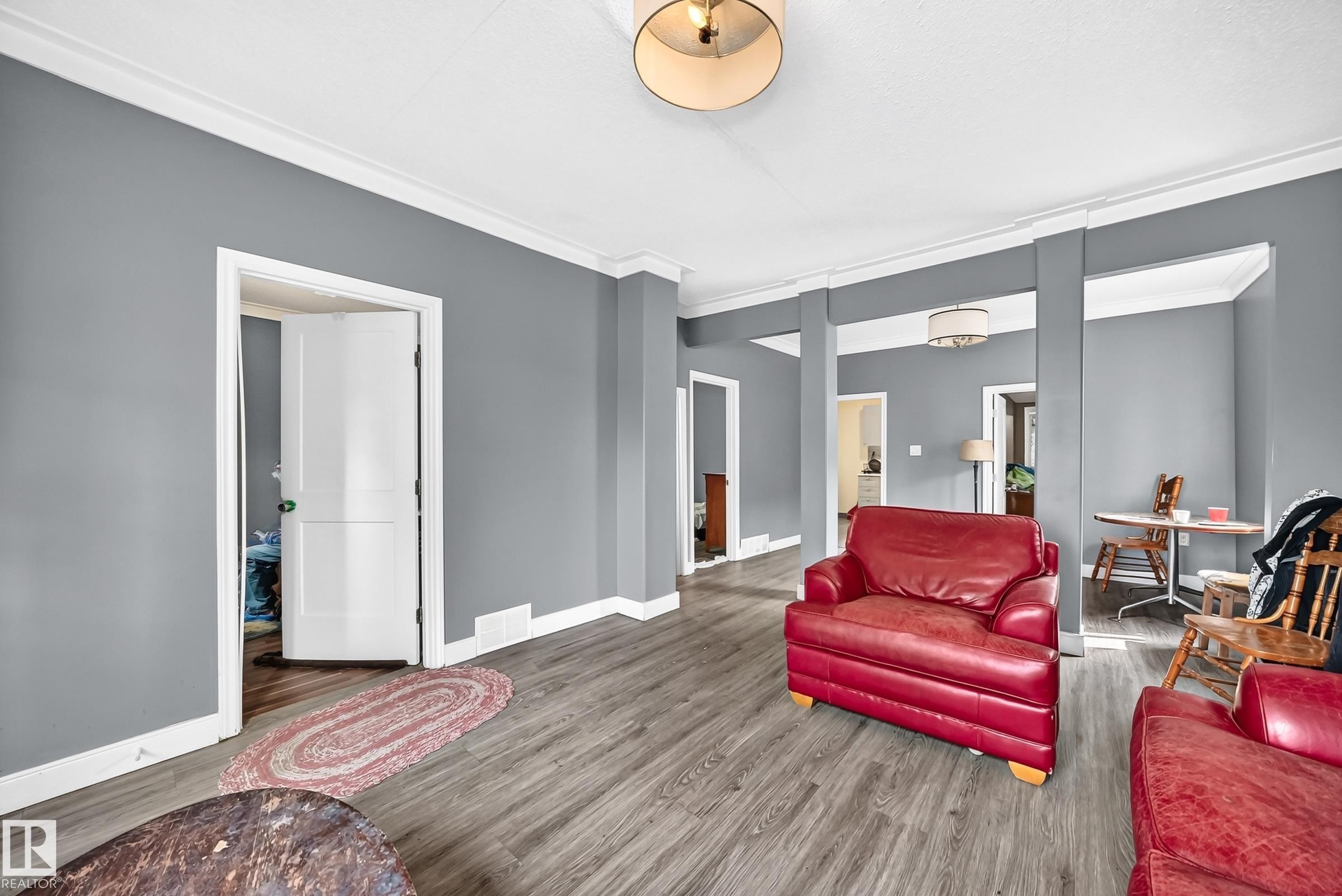Wood-finish flooring throughout, grey painted walls, white crown molding, and a drum pendant light fixture - 12627 71 Street Nw, Edmonton, AB