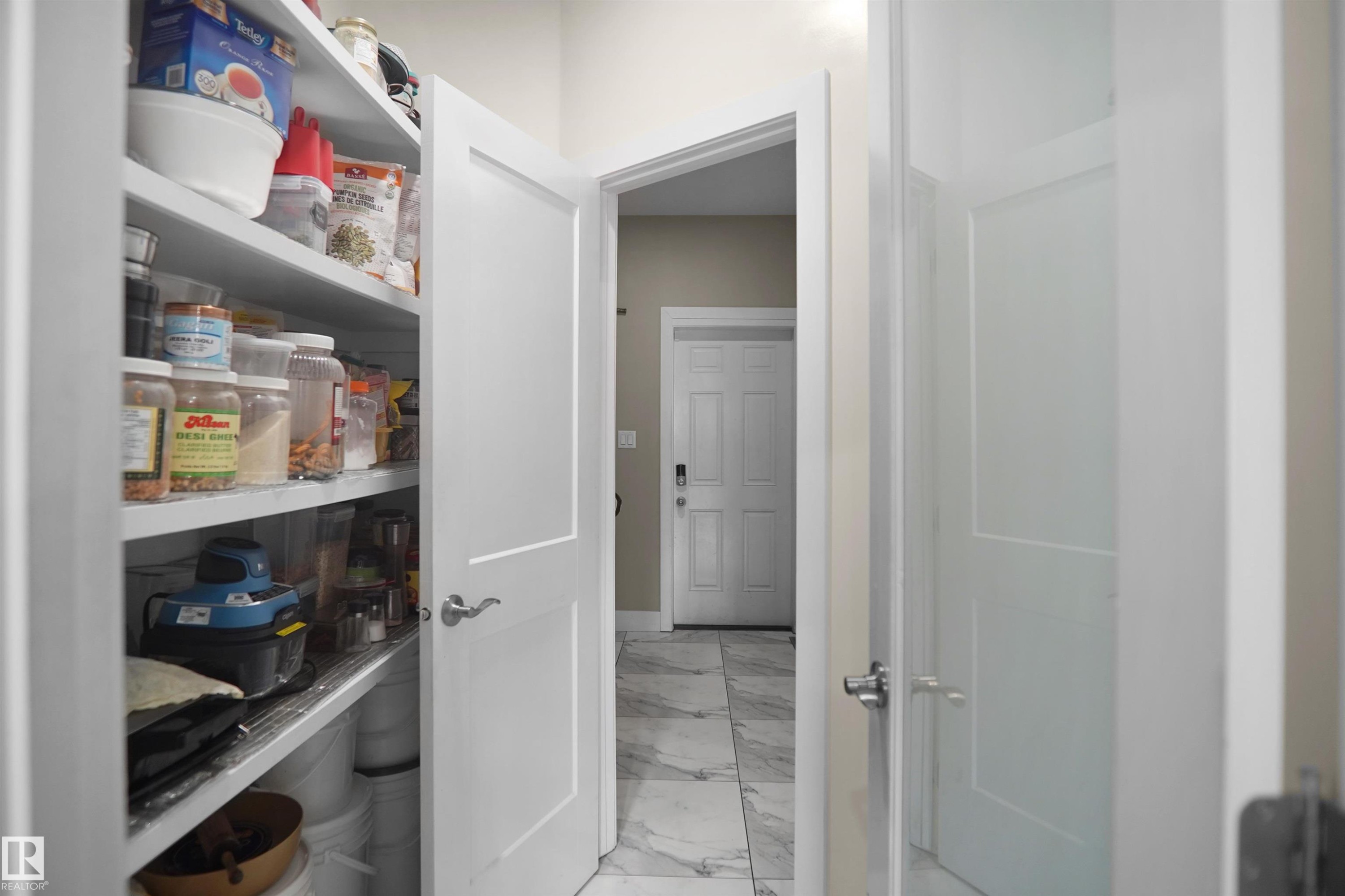Walk-in pantry with extensive shelving, a solid panel interior door, and brushed nickel hardware - 6108 173 Ave, Edmonton, AB - Indoor Photo Showing Other Room