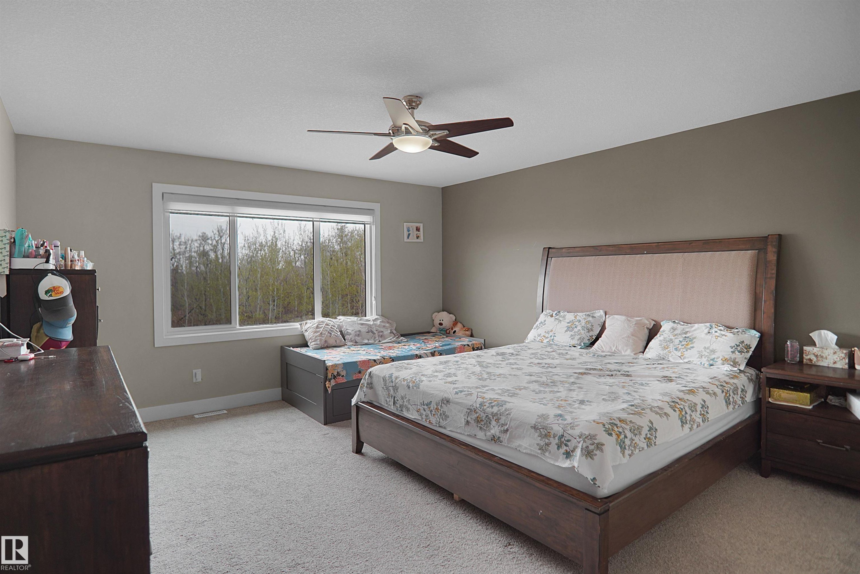 Carpeted bedroom featuring a large window, a ceiling fan with integrated lighting, and neutral wall tones - 6108 173 Ave, Edmonton, AB - Indoor Photo Showing Bedroom