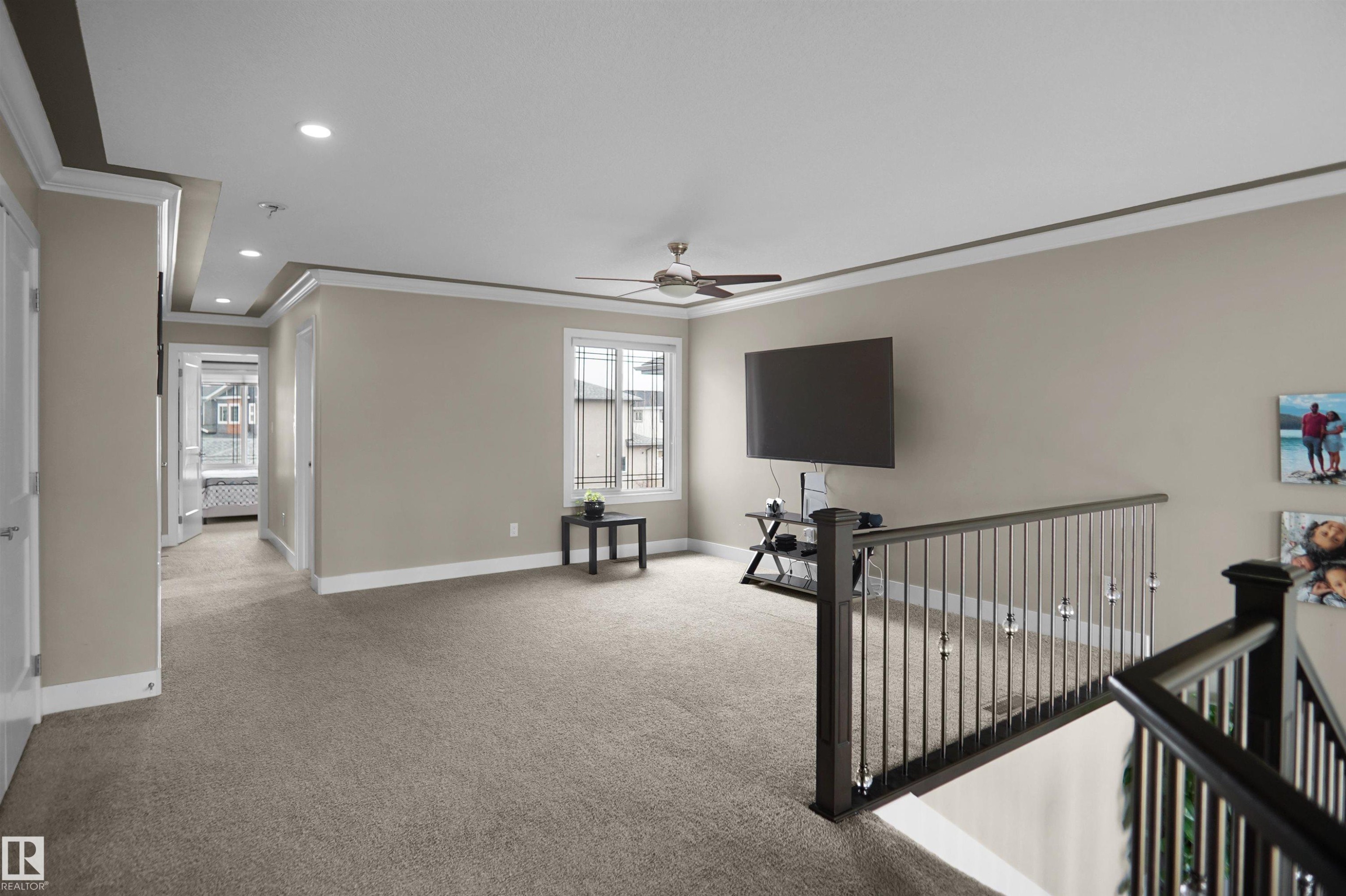 Upper-level landing featuring neutral carpeting, a tray ceiling with recessed lighting, and a modern ceiling fan - 6108 173 Ave, Edmonton, AB - Indoor Photo Showing Other Room