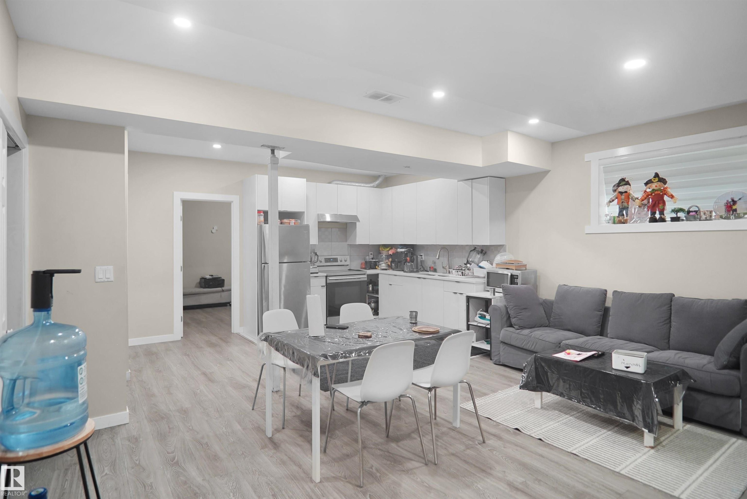 Open-concept living area featuring light wood-finish flooring, recessed lighting, and a kitchen with white cabinetry and stainless steel appliances - 6108 173 Ave, Edmonton, AB - Indoor Photo Showing Other Room