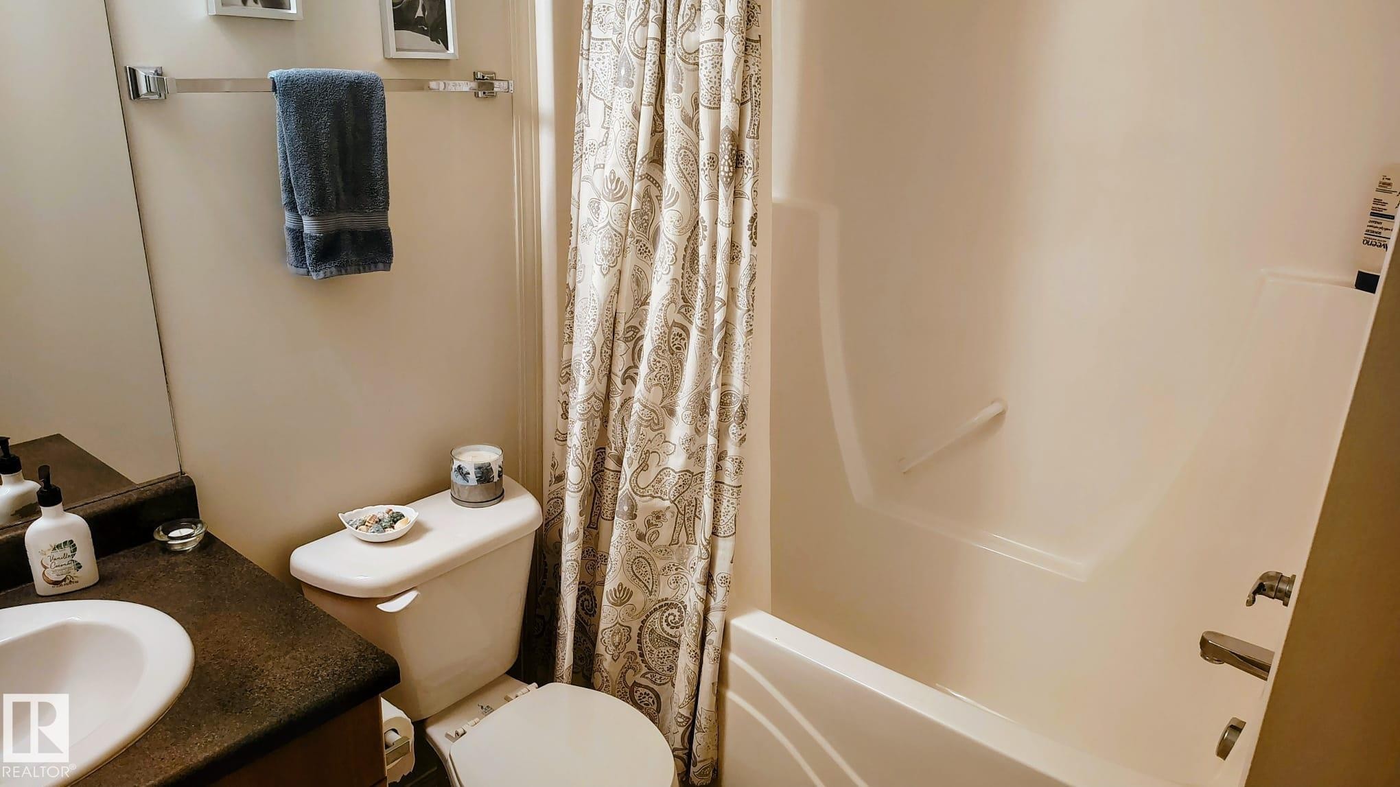 Bathroom featuring a vanity with an integrated sink, a toilet, and a shower-tub combination - 423 2430 Guardian Road, Edmonton, AB - Indoor Photo Showing Bathroom