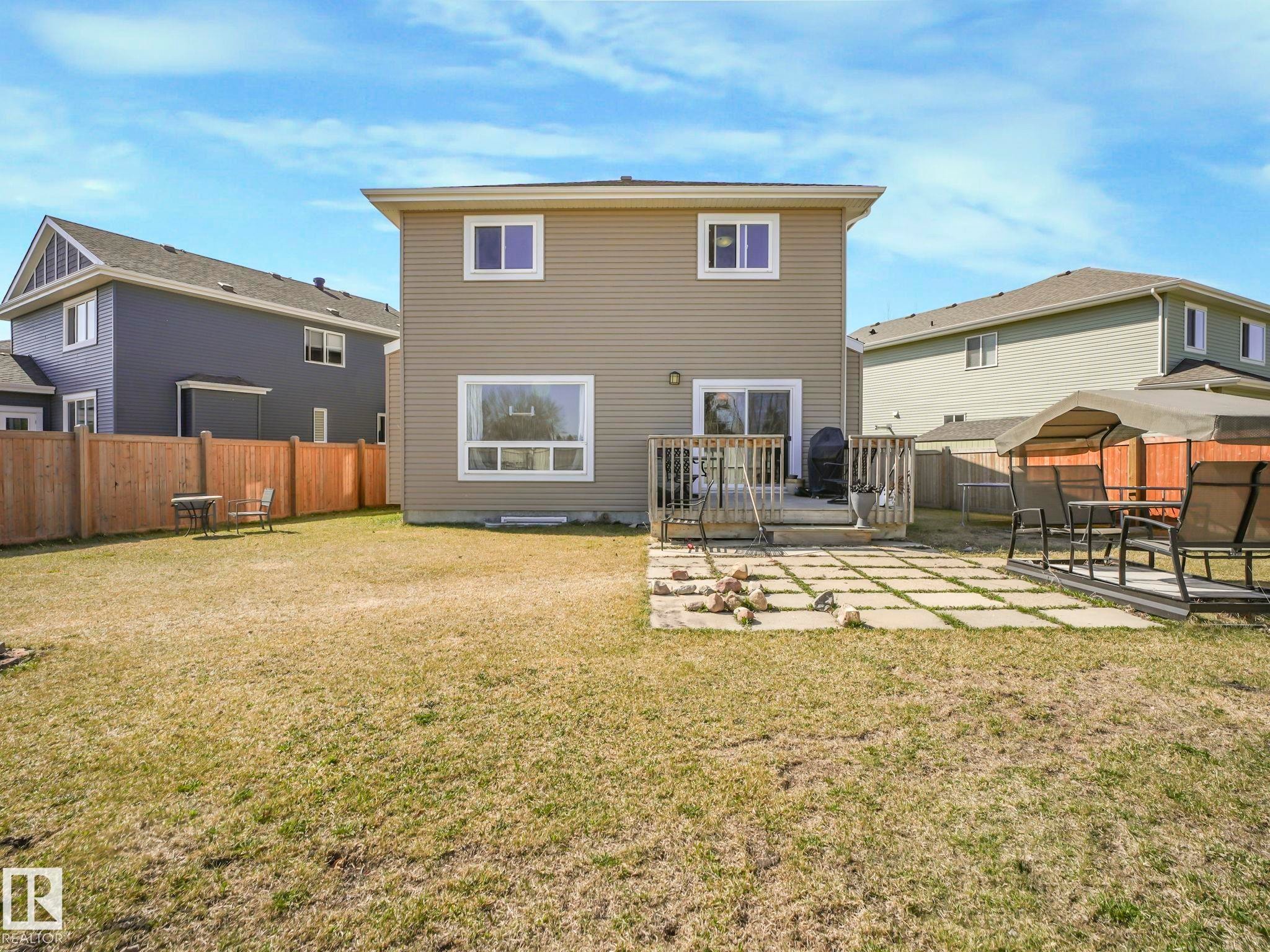 Expansive backyard featuring a wood privacy fence, a multi-level wood deck, and a ground-level concrete paver patio - 3910 49 Avenue, Beaumont, AB - Outdoor With Deck Patio Veranda With Exterior