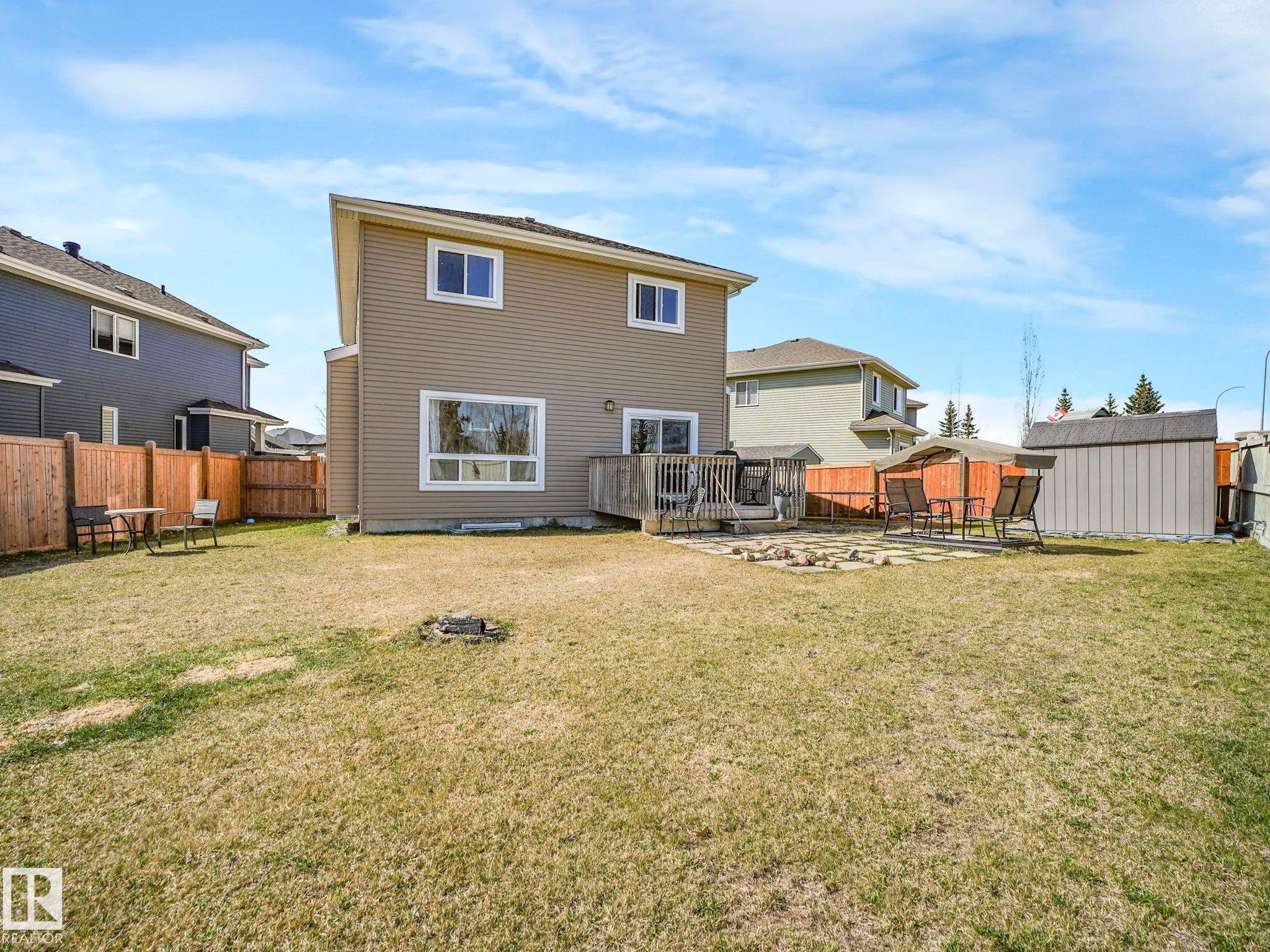 Expansive backyard featuring a wood deck, stone patio area, and a storage shed - 3910 49 Avenue, Beaumont, AB - Outdoor With Deck Patio Veranda With Backyard With Exterior