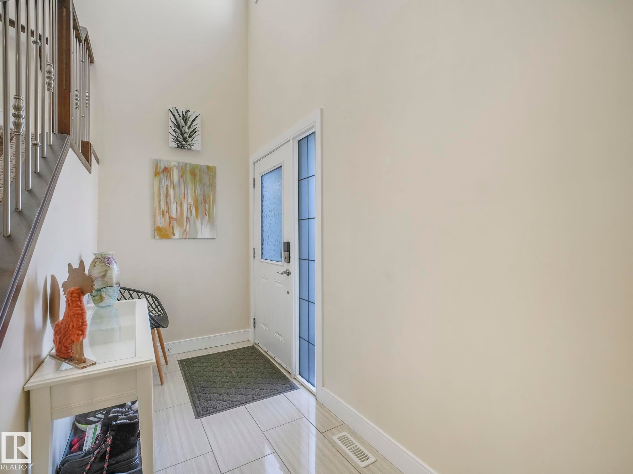 Entryway featuring light-toned walls, light-colored tile flooring, and a white front door with decorative glass inserts - 3910 49 Avenue, Beaumont, AB - Indoor Photo Showing Other Room