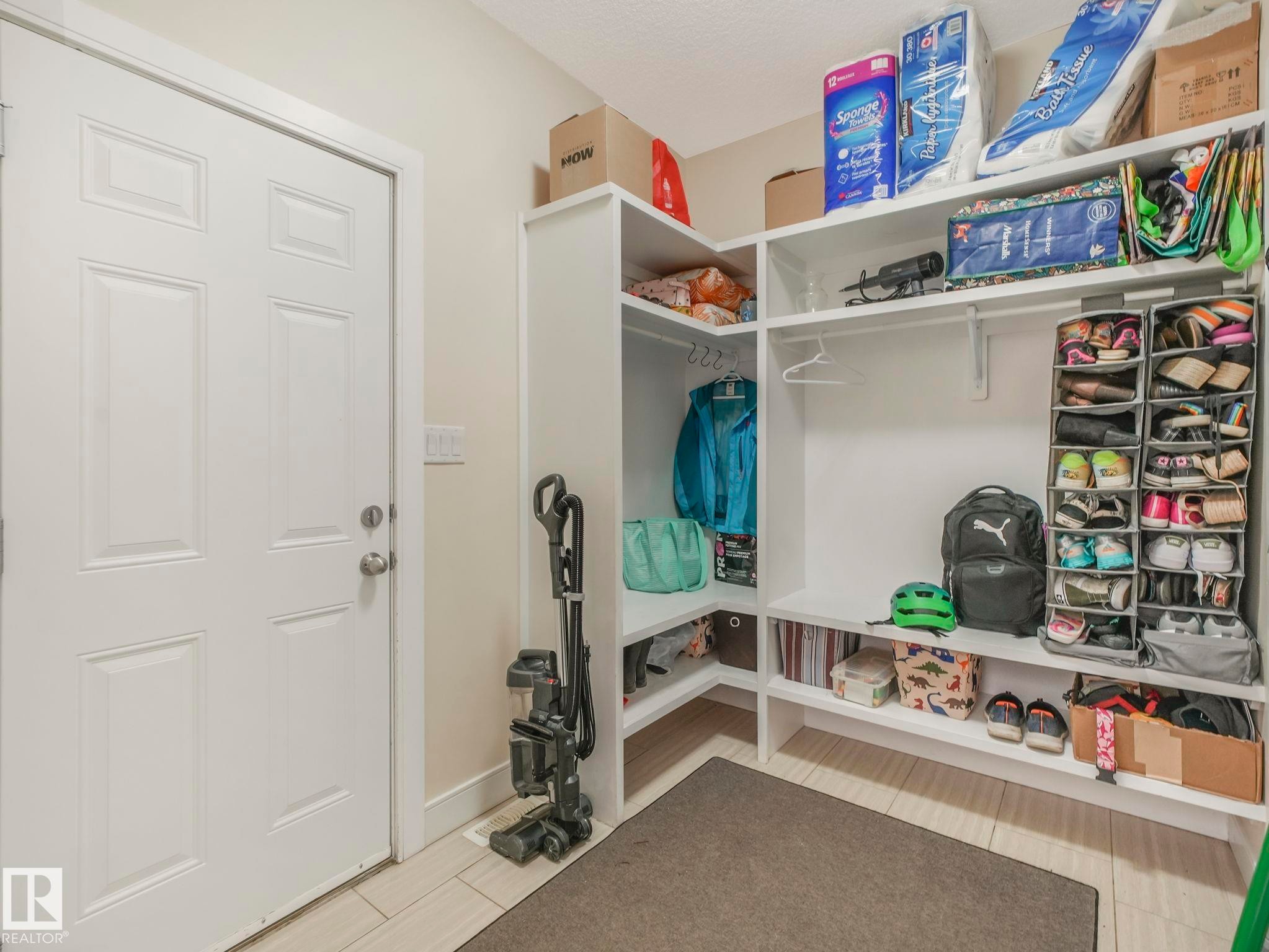 Built-in shelving unit with multiple storage levels, a hanging rod, and integrated shoe storage - 3910 49 Avenue, Beaumont, AB - Indoor
