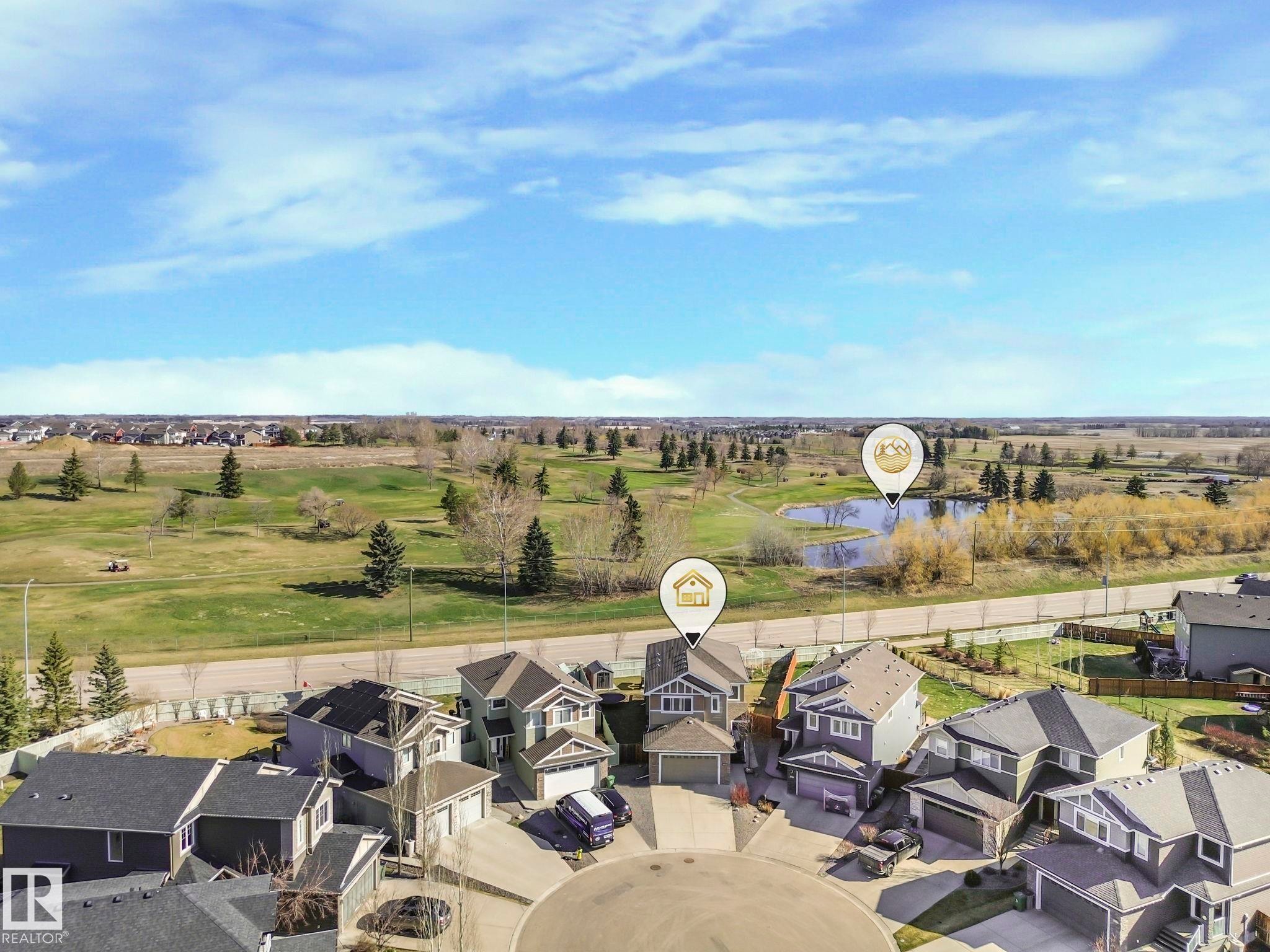Cul-de-sac residence featuring a multi-car driveway, attached garage, and a rear yard backing onto a manicured golf course with a prominent pond and mature trees - 3910 49 Avenue, Beaumont, AB - Outdoor With View