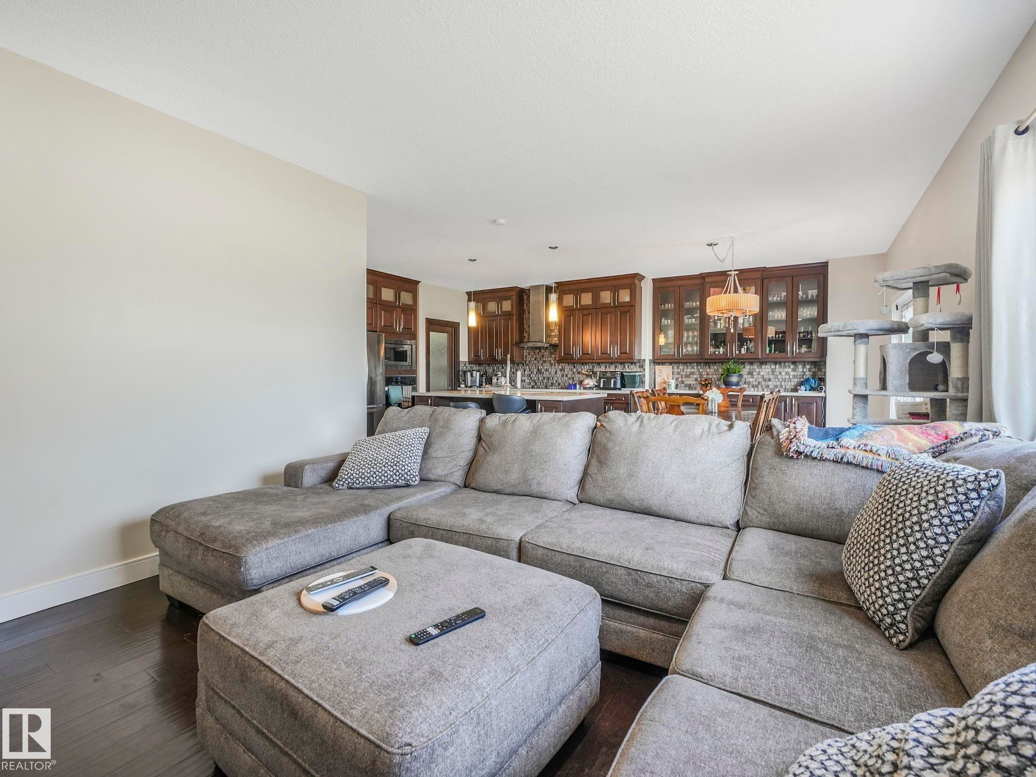 Open-concept living space featuring dark wood-finish flooring, light neutral wall tones, and recessed ceiling lighting - 3910 49 Avenue, Beaumont, AB - Indoor Photo Showing Living Room